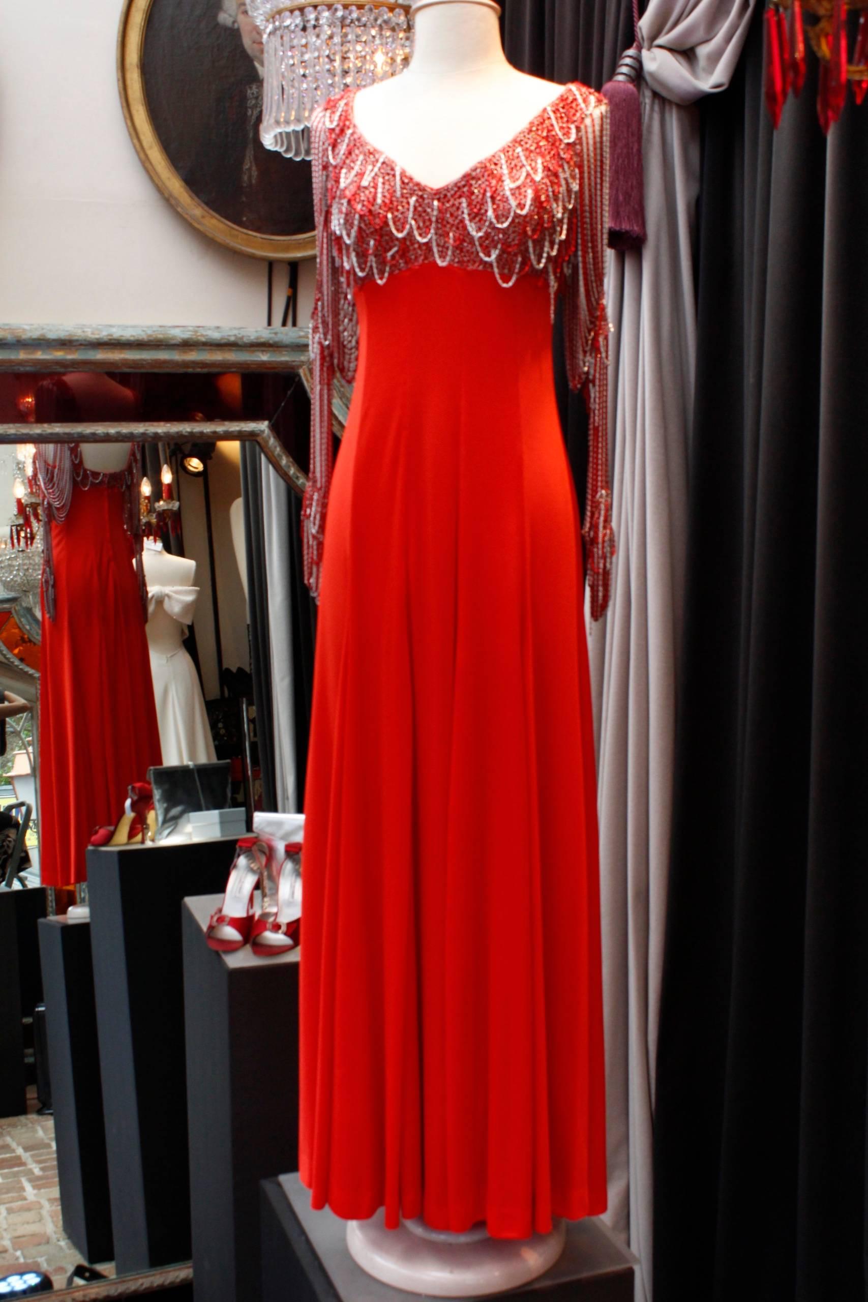 LORIS AZZARO (Attributed to) Long red jersey evening dress. The bust is covered with red and silver lurex knit decorated with silver and red chains. The long sleeves are composed of similar thin red and silver chains. Back zip closure. No