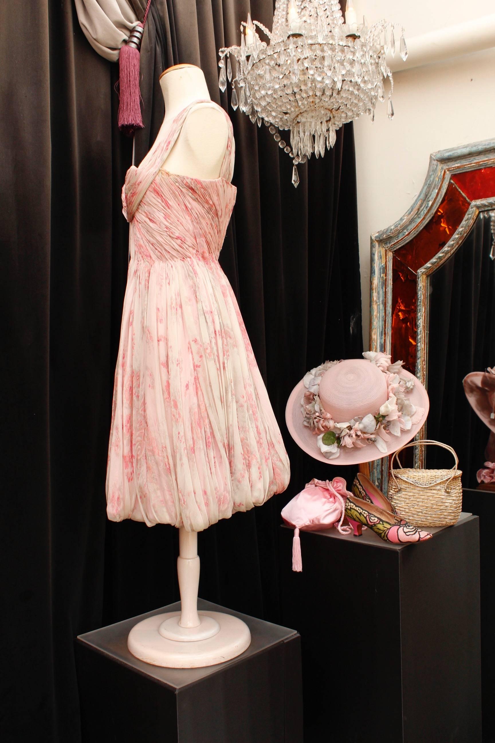 CARVEN HAUTE COUTURE (Made in France)  Gorgeous cocktail dress entirely hand stitched, made of pink silk chiffon with floral pattern. The pleated dress features hand stitched gathers, a slightly rigid bustier and two straps crossing under the bust.