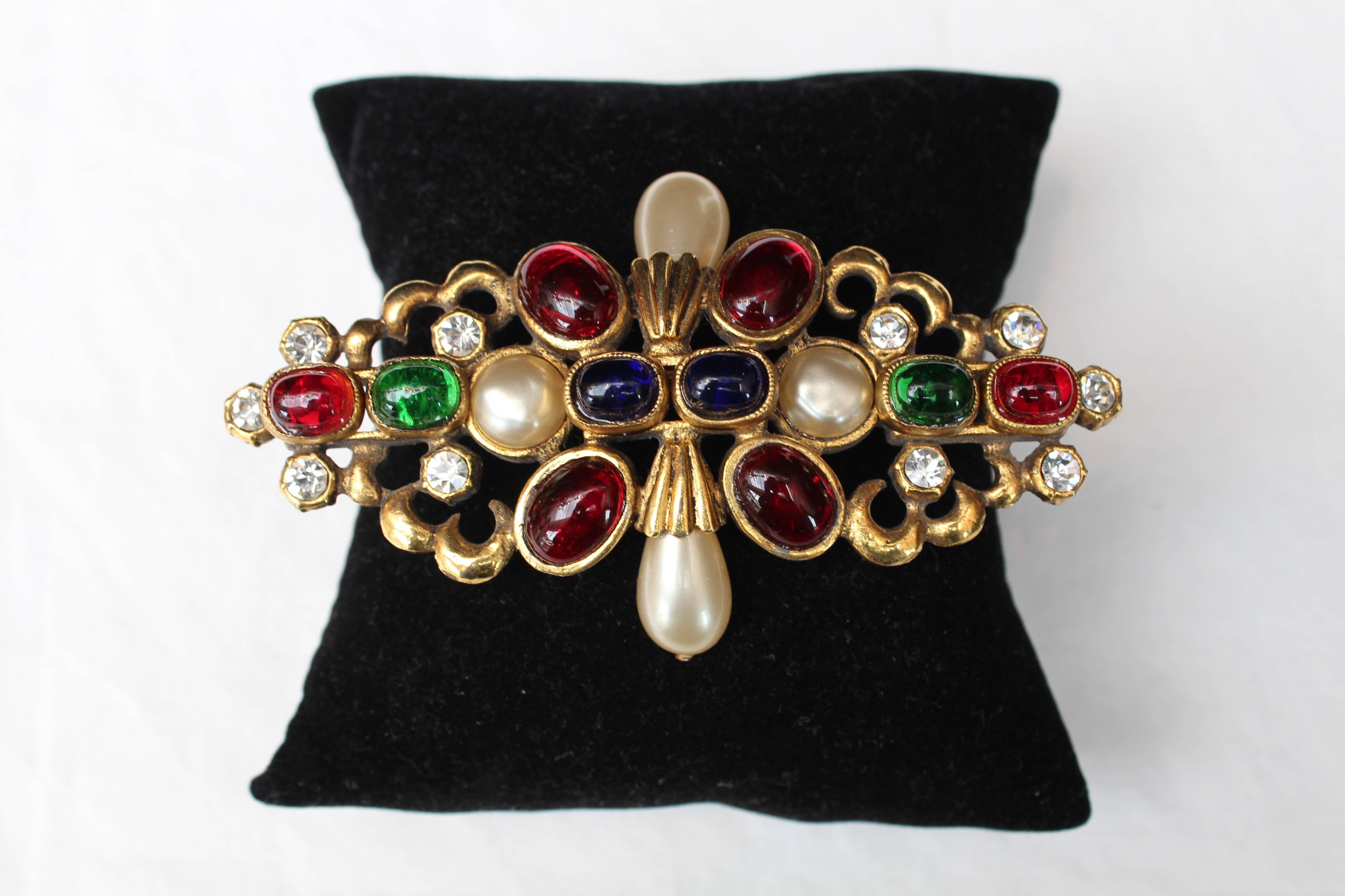 CHANEL (Made in France) - Brooche composed of blue, green and red glass paste cabochons with faux pearls and rhinestones.The basis is made of engraved gilted metal.

Signed at back.

Fall 1984.

Very good condition.


10 cm (3.94 in) x 5.5 cm (1.9