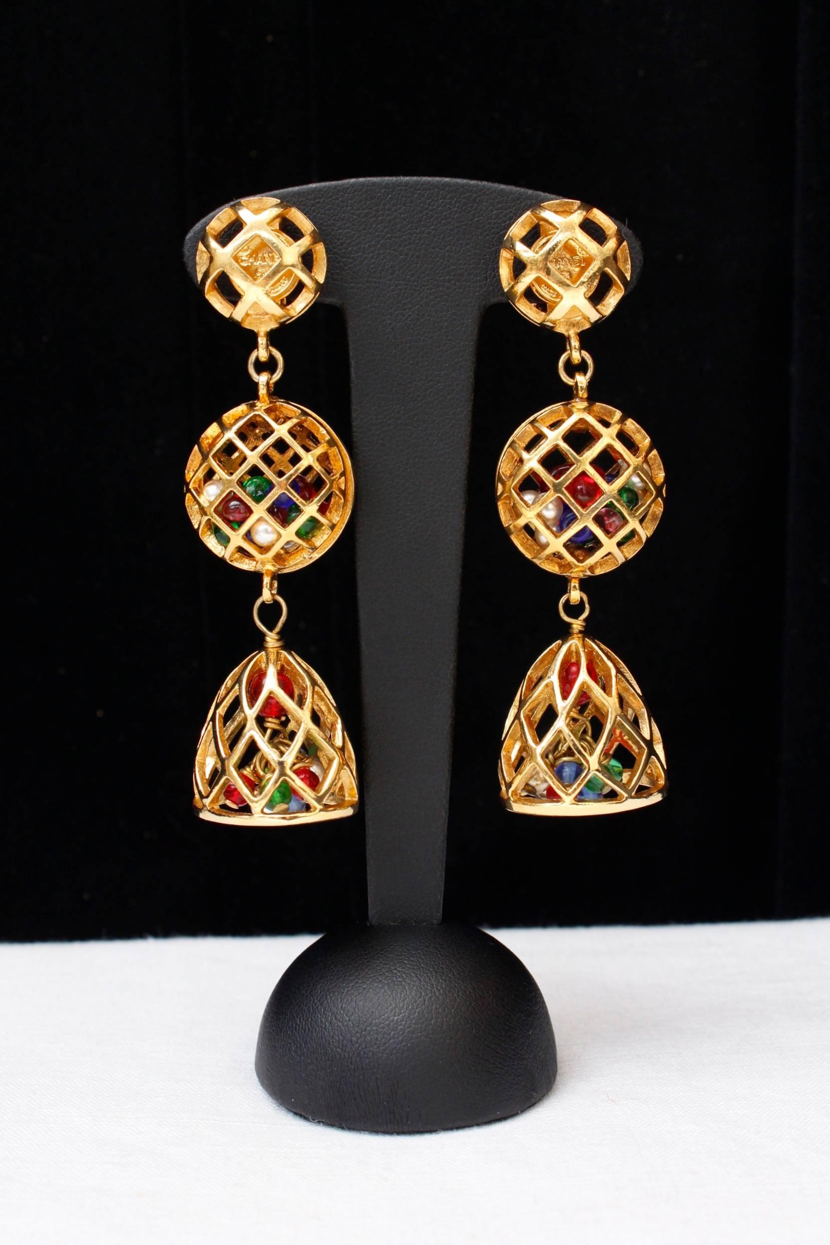 CHANEL (Made in France) pair of drop clip-on earrings composed of three gilded metal cages, including one in the shape of a bell. These cages are full of small red, green blue and pearly beads.

Signed on plate.

Circa late 1980s.

Very good