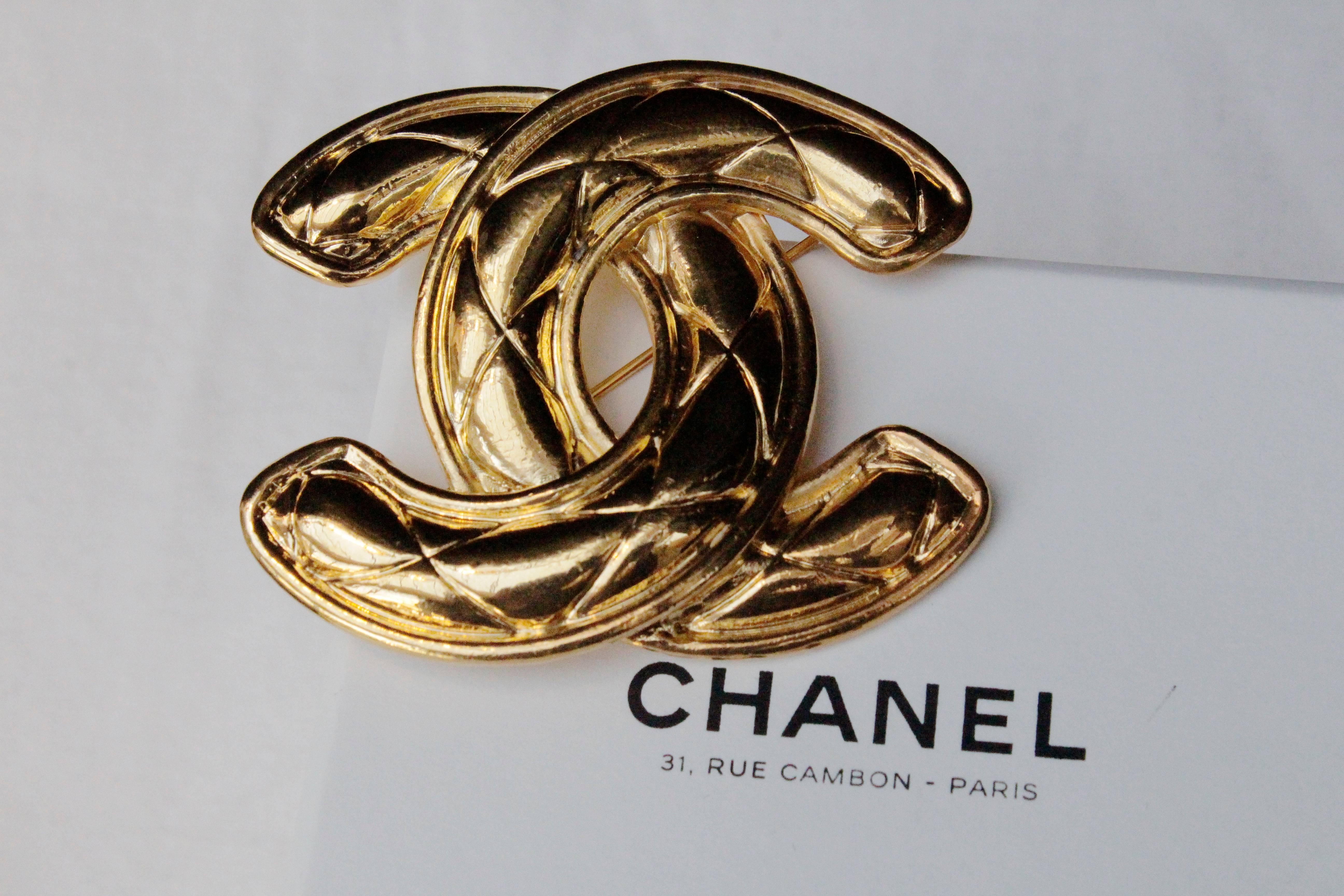 CHANEL (Made in France) Large chiseled gilded metal brooch representing a quilted CC logo. Signed at back.

Circa 1990.

Measurements 5 x 6 cm (2 x 2.25 in).

Very good condition.