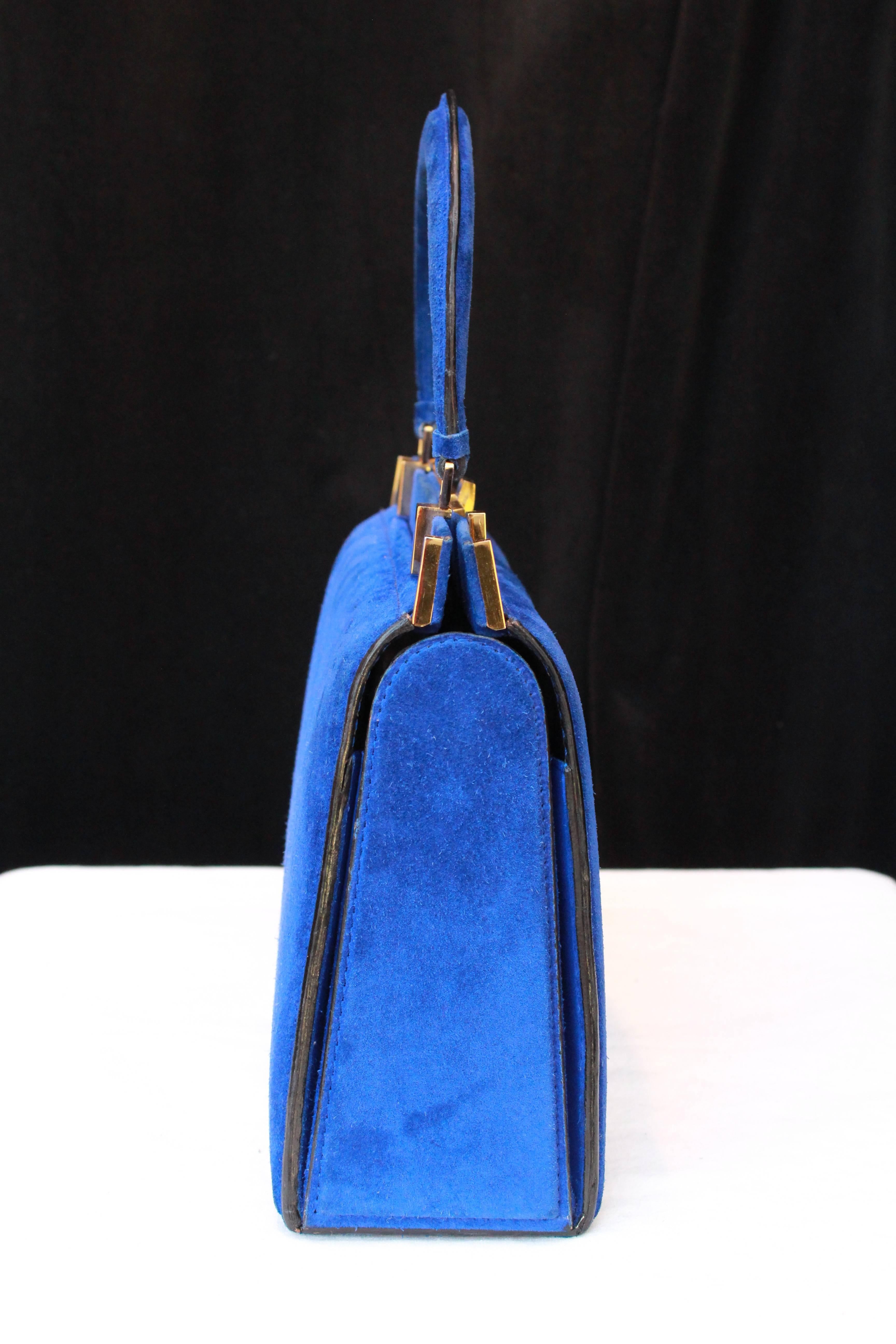 FERNANDE DESGRANGES (Made in France) Trapezoid handbag in electric blue suede and gilded metal hardware. Black leather lining, with two compartments separated by a zipped pocket , one patch pocket with a round snap.

Signed “Genève Paris Nice –
