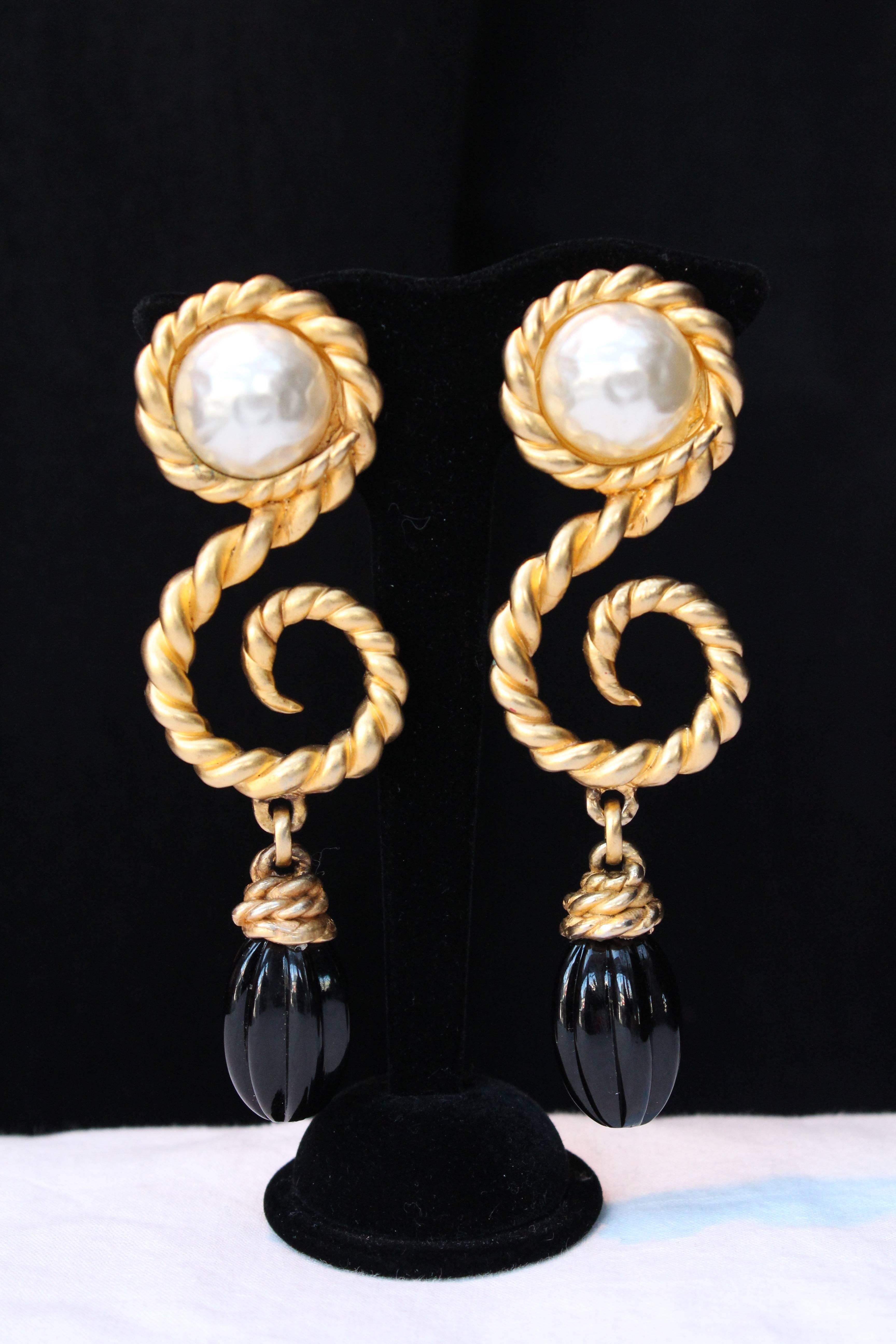 CHANEL (Made in France) Dramatic gold plated earrings made of strong golden rod like a treble clef and decorated with a pearly cabochon and a black glass paste drop.

From 1985 - 1990s.

Size : 12 cm ( 4,72 in ) x 3.5 cm ( 1.18 in )
 
Very good