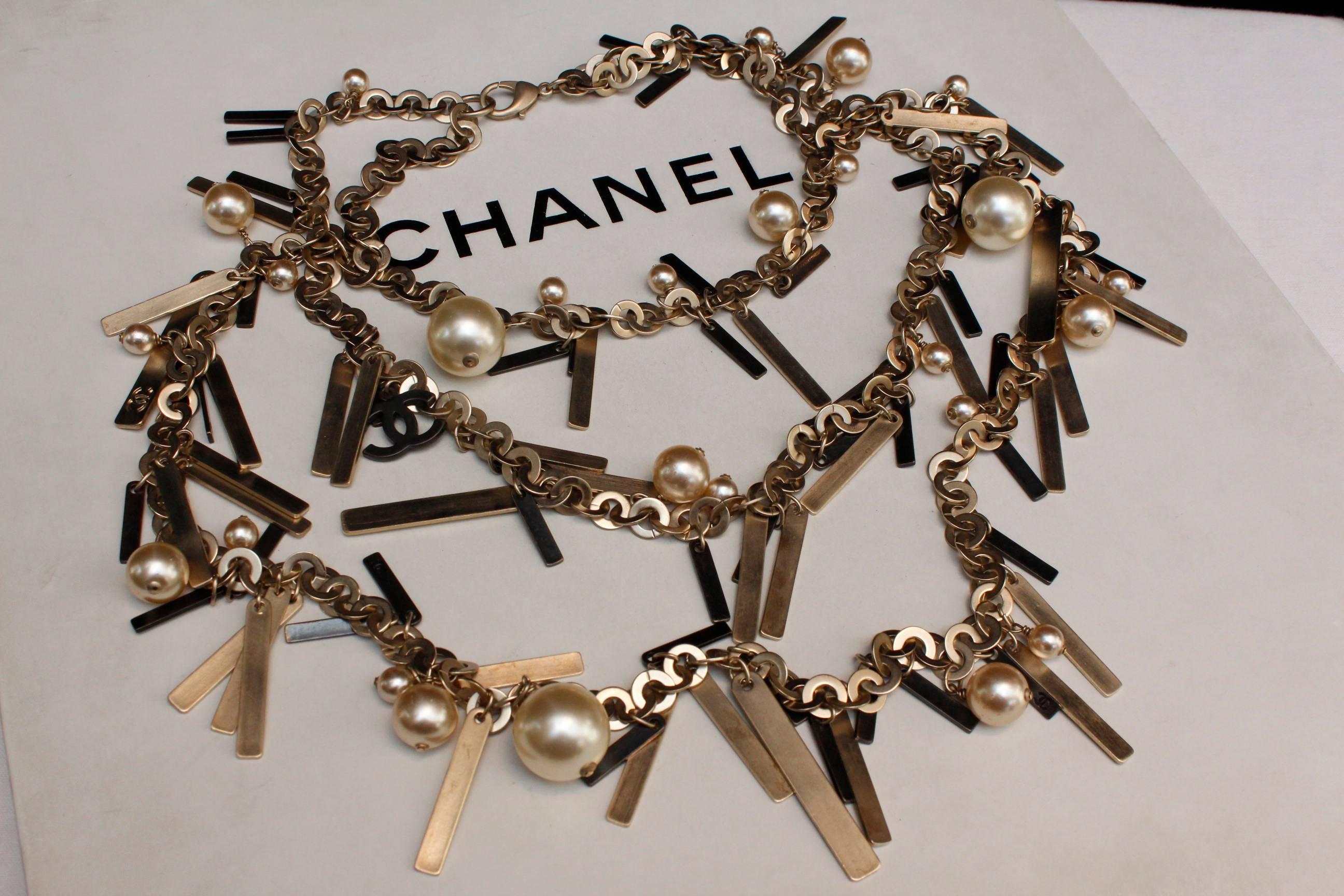 CHANEL (Made in France) Three strand necklace composed of silver/gold rings decorated with multiple blackened silver plate and golden thin strips as well as pearly beads and some blackened CC logo pendants.

2003 Spring Collection, as indicated on