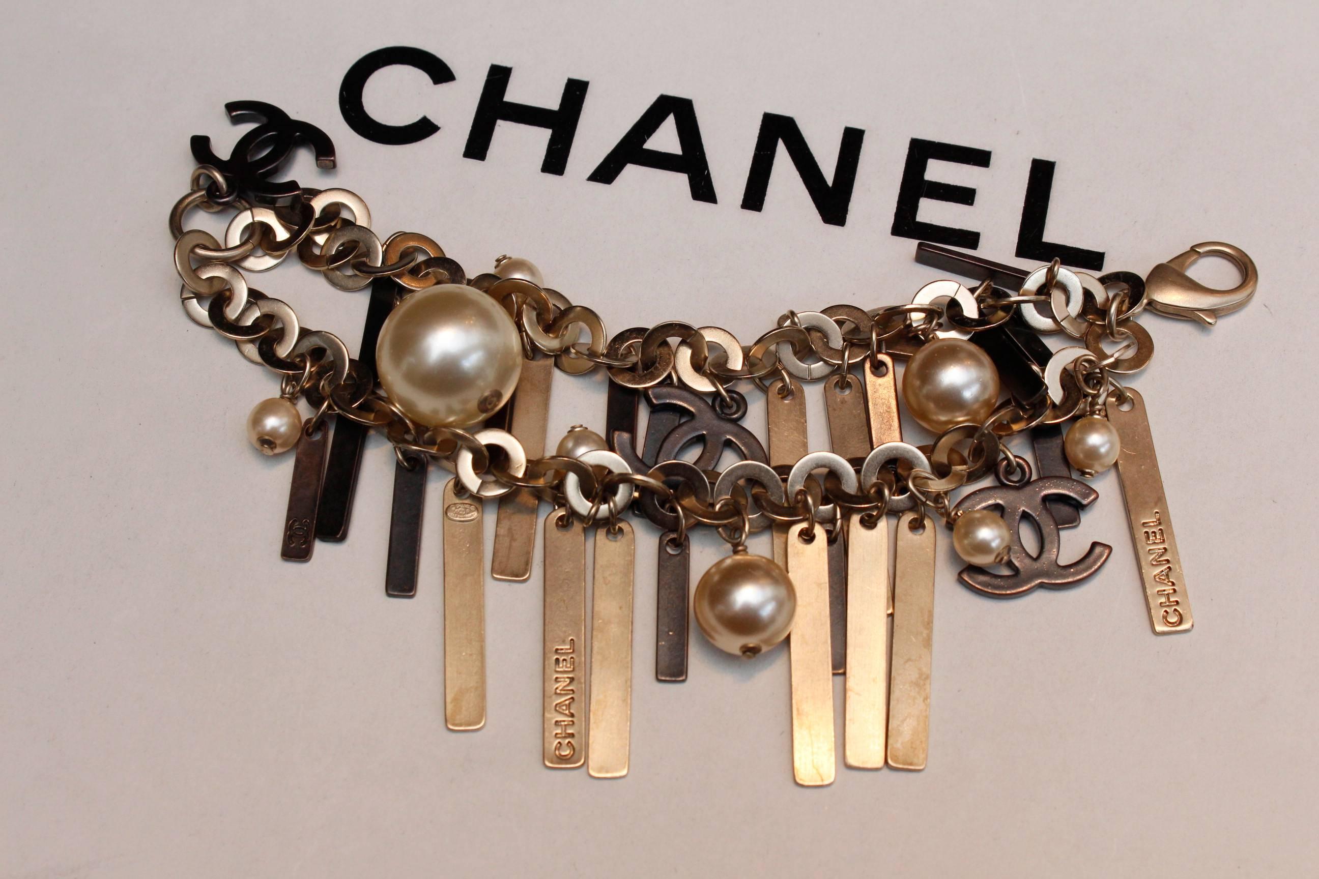 CHANEL (Made in France) Bracelet composed of two strands of silver/gold rings decorated with multiple blackened silver plate and gold thin strips, and with pearly beads and a few blackened CC logos.

2003 Spring Collection, as indicated on the