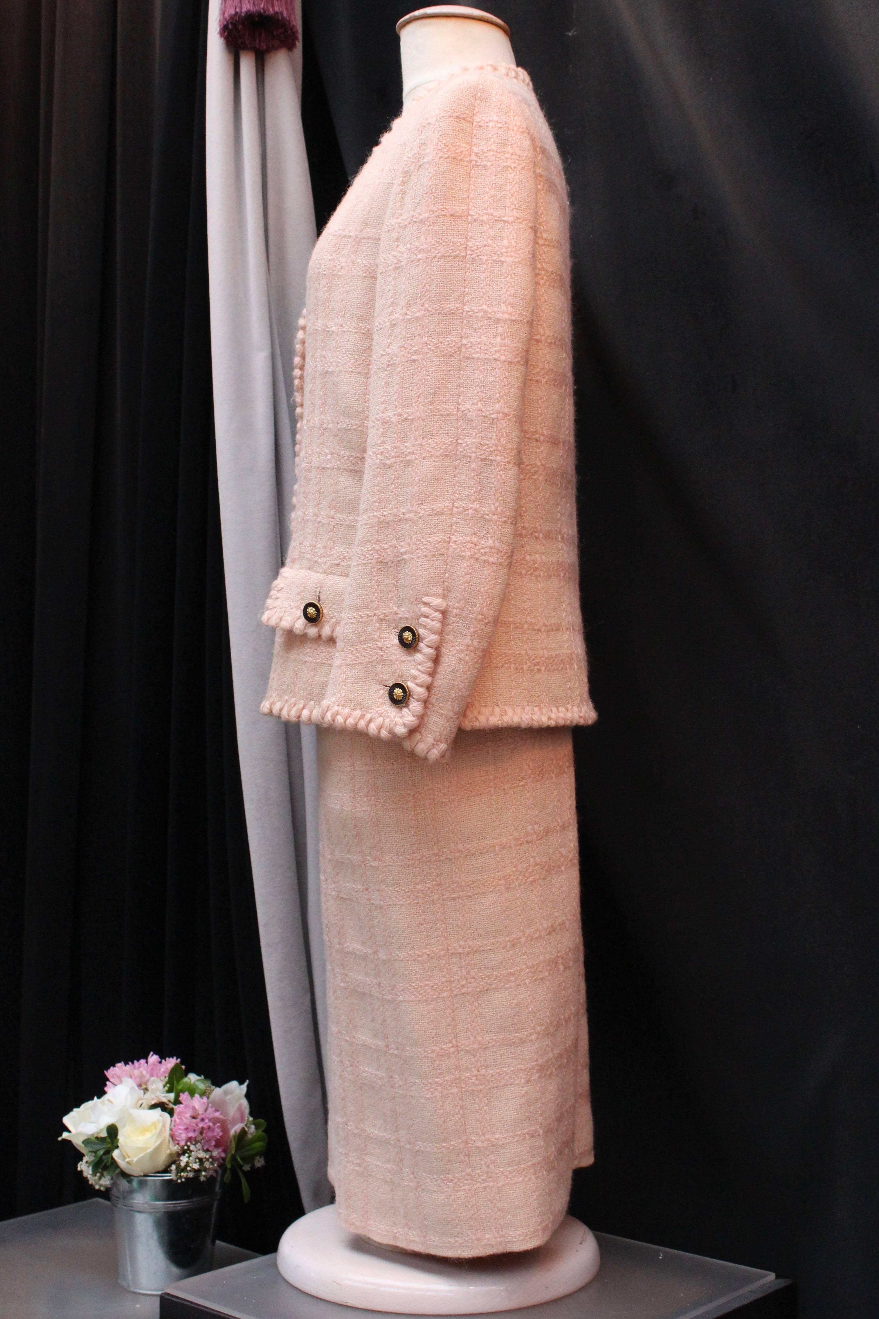 Chanel Haute Couture (Made in France)  Vintage light pink wool tweed set comprised of a skirt and a jacket.

The long sleeves V-neck jacket fastens with six round gilded metal and black resin buttons with a golden lion head in the center. The same