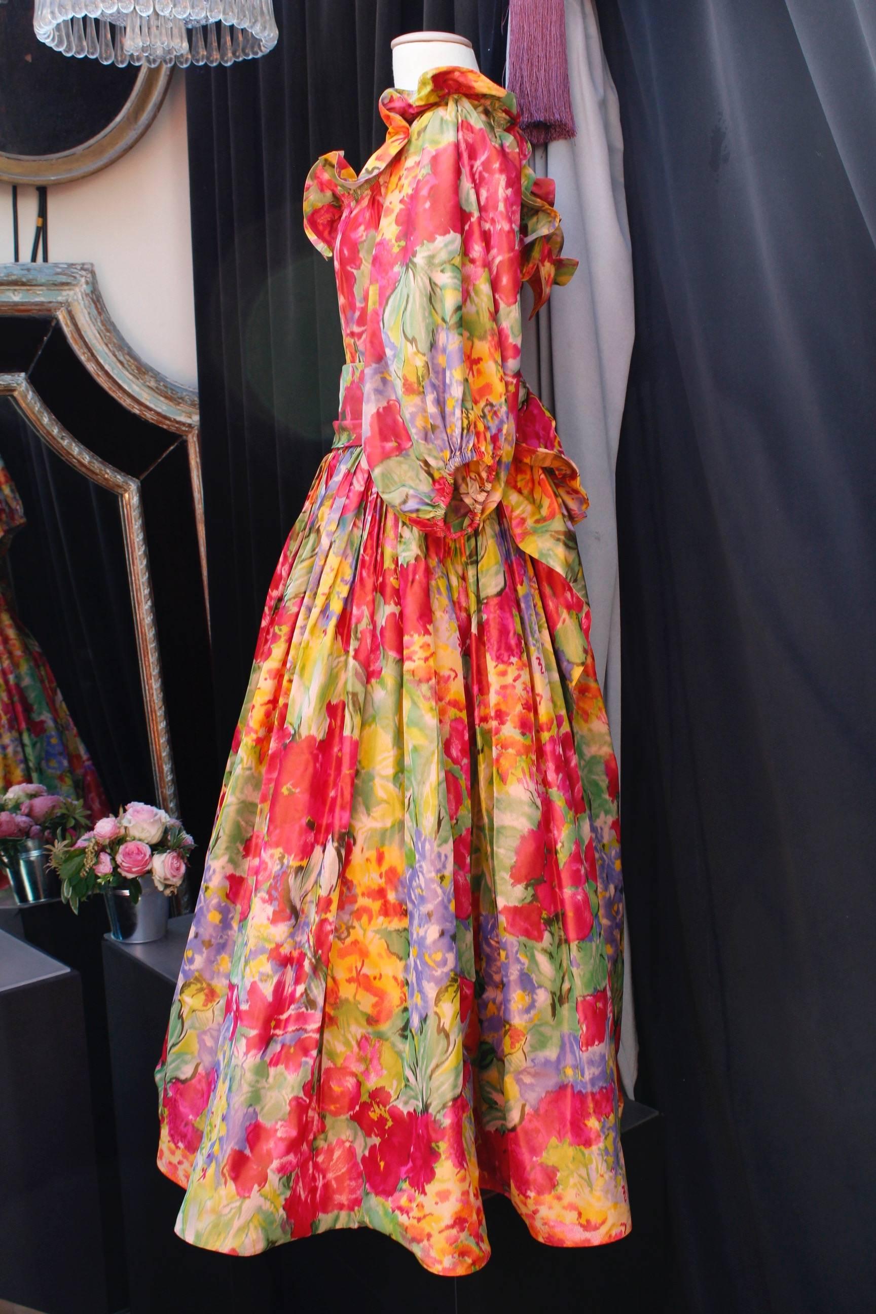 NINA RICCI – Attributed to ( Made in France ) – Stunning opera dress composed of silk taffeta with floral pattern print in red, yellow, green, purple and orange tones. The top features a boat neck underlined with a large flounce, and three-quarter
