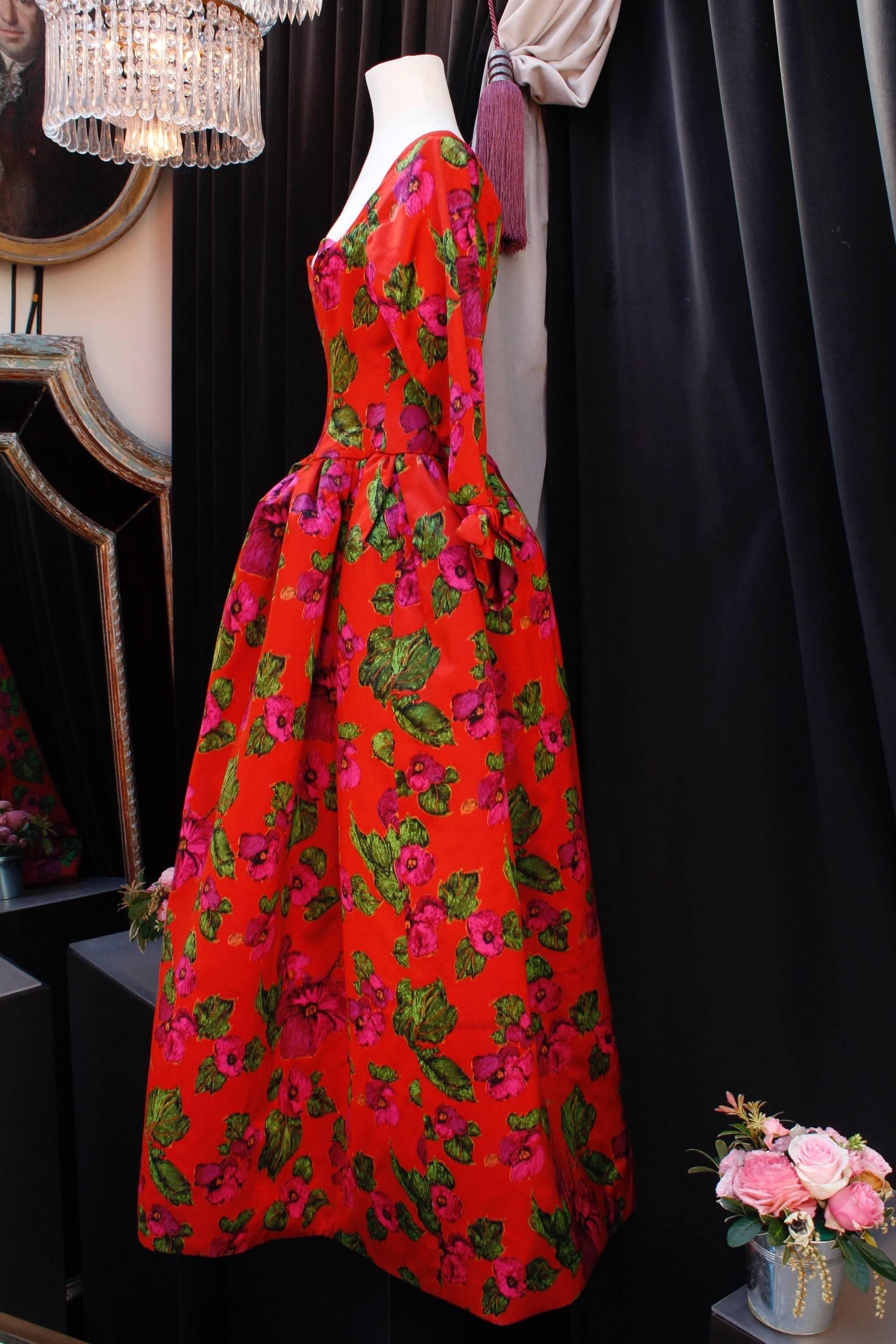 NINA RICCI (Made in France) Stunning opera dress composed of orange red silk taffeta. The top features a close-fitting cut with a heart-shaped neck and long tight sleeves with a bow on their cuffs. The gored skirt is flared, from the waist to the