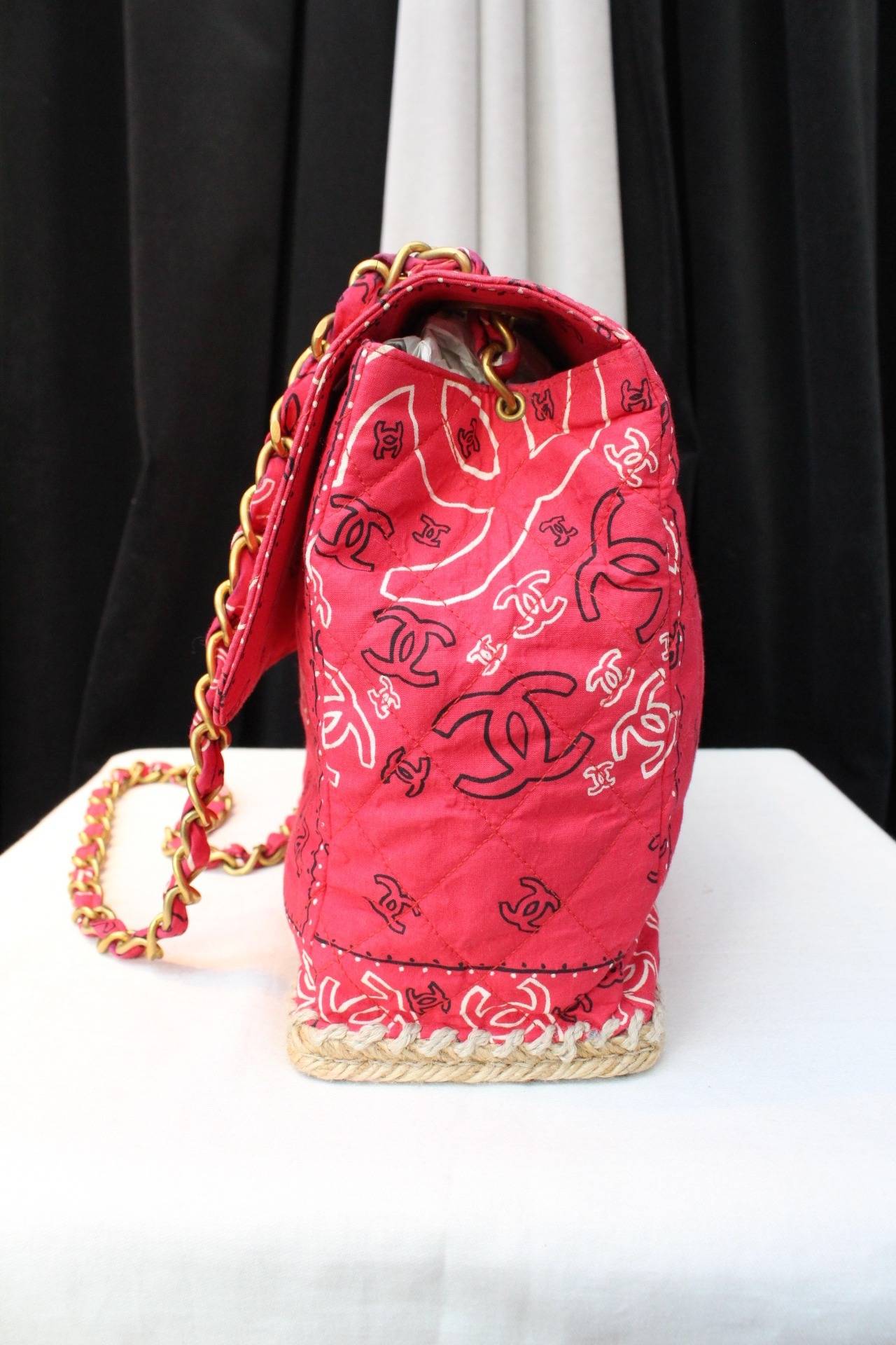 Limited edition Maxi Jumbo Chanel Bag from the 1990s composed of cotton canvas with a red CC Logo Bandana print, and a jute rope sole. 

The bag is adorned with an inner black canvas patch pocket and one zipper pocket. It is also composed of a