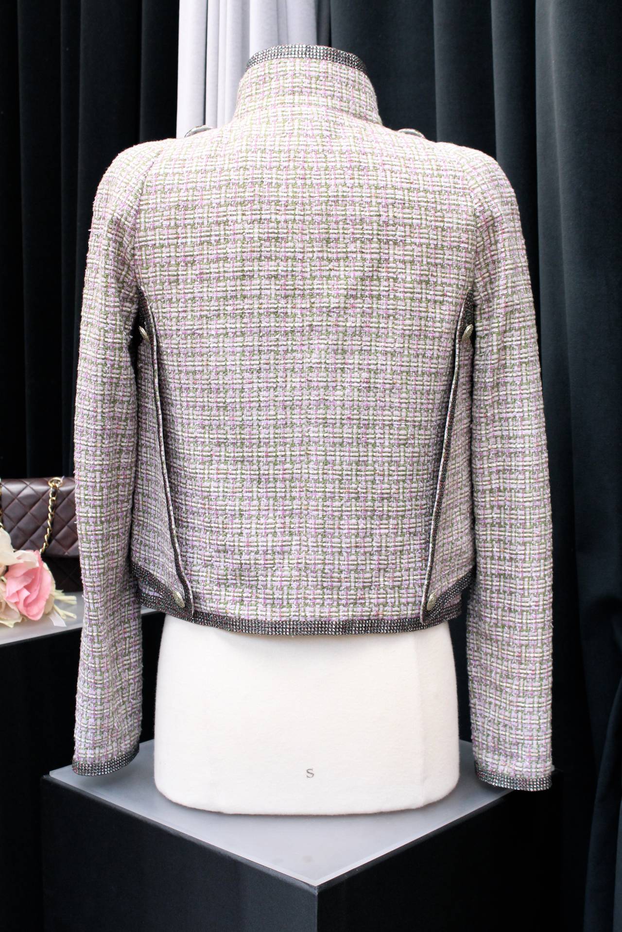Chanel jacket from the 2011 spring collection, Look 27 of the runway, composed of light pink and green tweed adorned with strips of rhinestones embroideries and silver metal and enamel buttons.
The jacket is constructed with several elements 