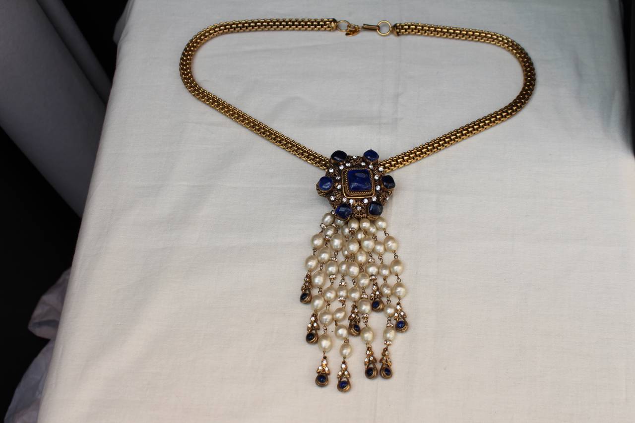 Rare Chanel necklace from the 1960s/1970s composed of a gold metal chain and a pendant with a medallion and dripping faux pearls ended by Gripoix blue glass paste beads. 

The medallion is composed of gold openwork and chiselled metal adorned with