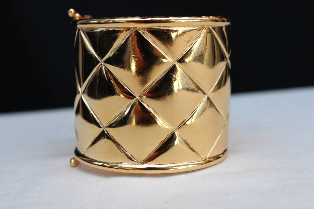 Super chic pair of Chanel cuffs from the 1990s composed of quilted chiseled gold metal. 

They open on the side thanks to an articulated rod and two clasps on the other side. 

Very good condition (with the exception of few wearing marks on the