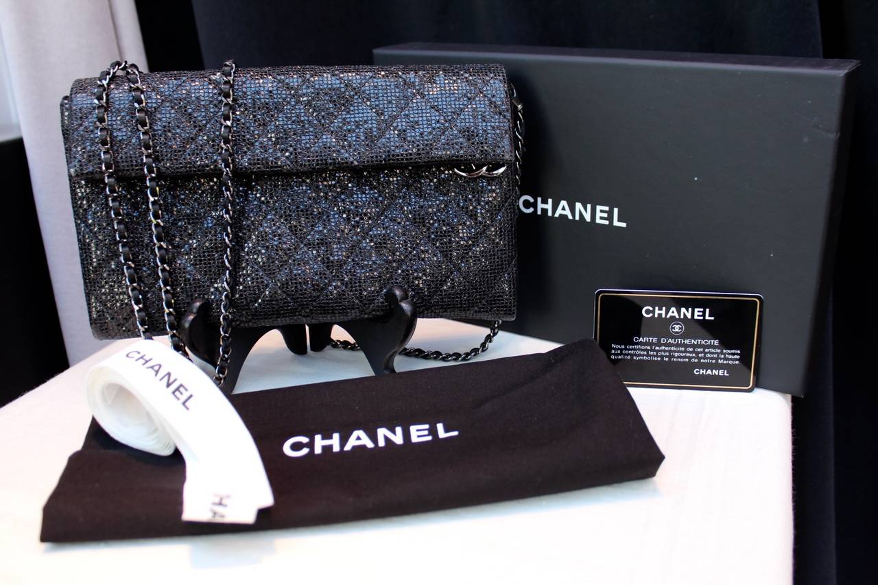 Chic Evening Bag Chanel (Made in Italy) from December 2014, composed of quilted black iridescent fabric and ruthenium chain interlaced with a black leather strap. 
Black silk inner lining comprising of a zip pocket and two phone pockets and the