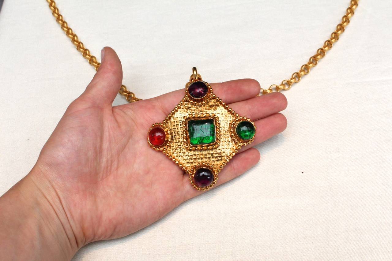 Gorgeous pendant necklace by Isabel Canovas from the 1980s composed of a gold chain holding a diamond shape pendant in chiseled gold metal adorned with red, green and violet glass paste cabochons. 

The label is marked in the back of the pendant.