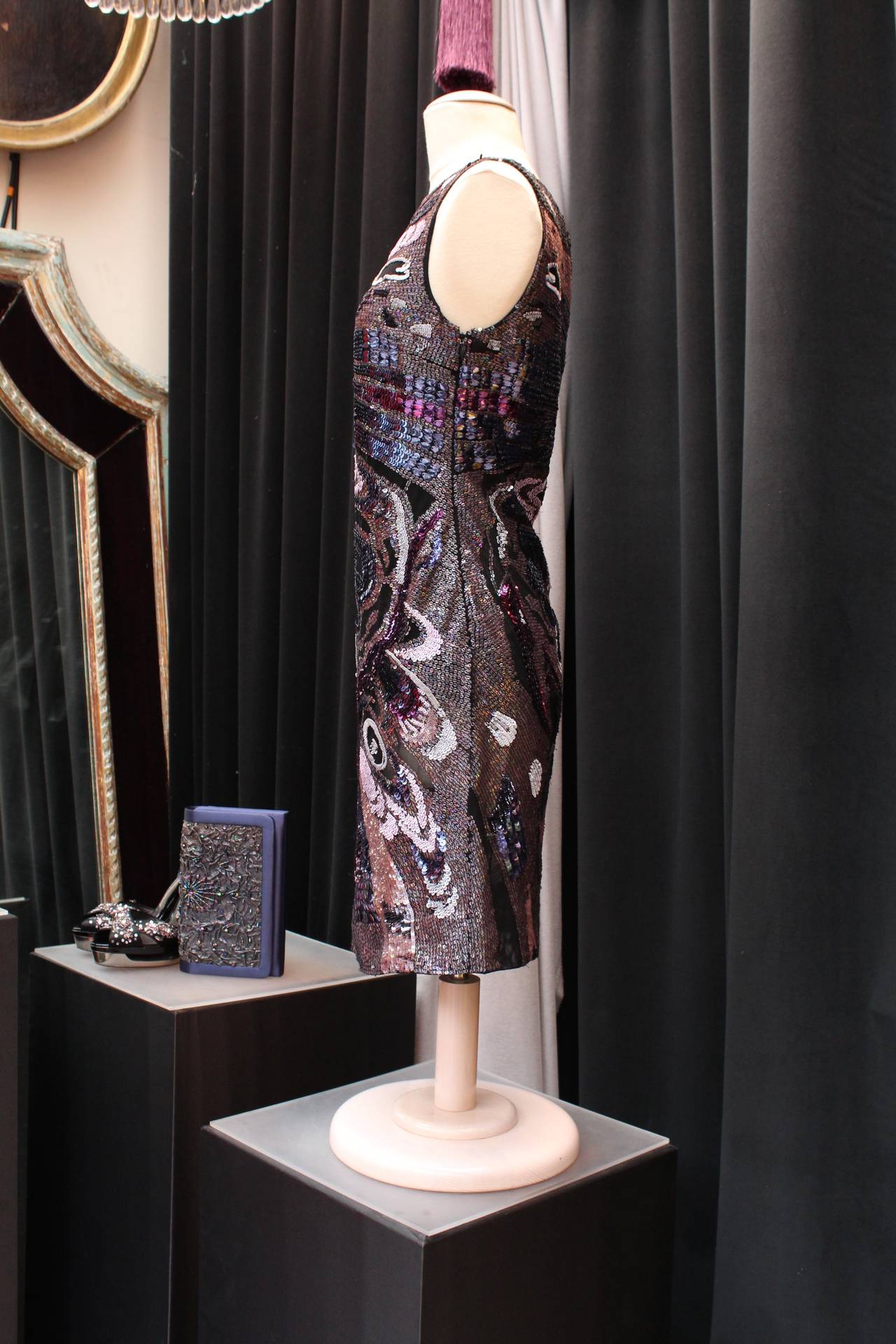 EMILIO PUCCI (Made in Italy) Short sleeveless dress composed of black tulle entirely covered in shiny sequins pink, blue, black, pale pink and auburn figuring a psychedelic and glam rock pattern .
The dress closes thanks to a black zipper on the