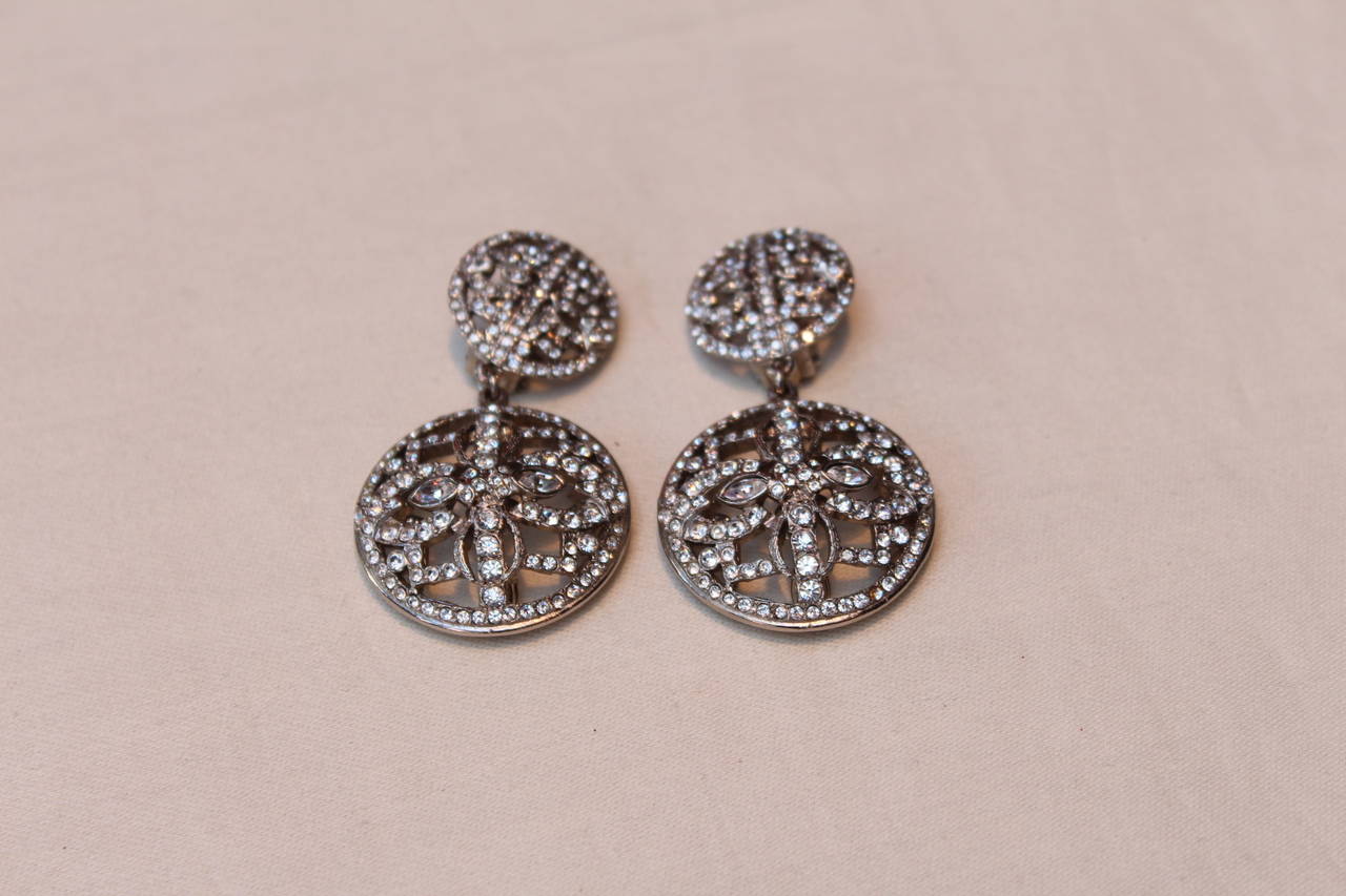 Stunning clip-on earrings Christian Dior Boutique from the 1990s, composed of two openwork demi-spheres in silver metal paved with round and marquise shape white crystals.

The back of the pendant sphere is adorned with 5 marquise shape crystals.