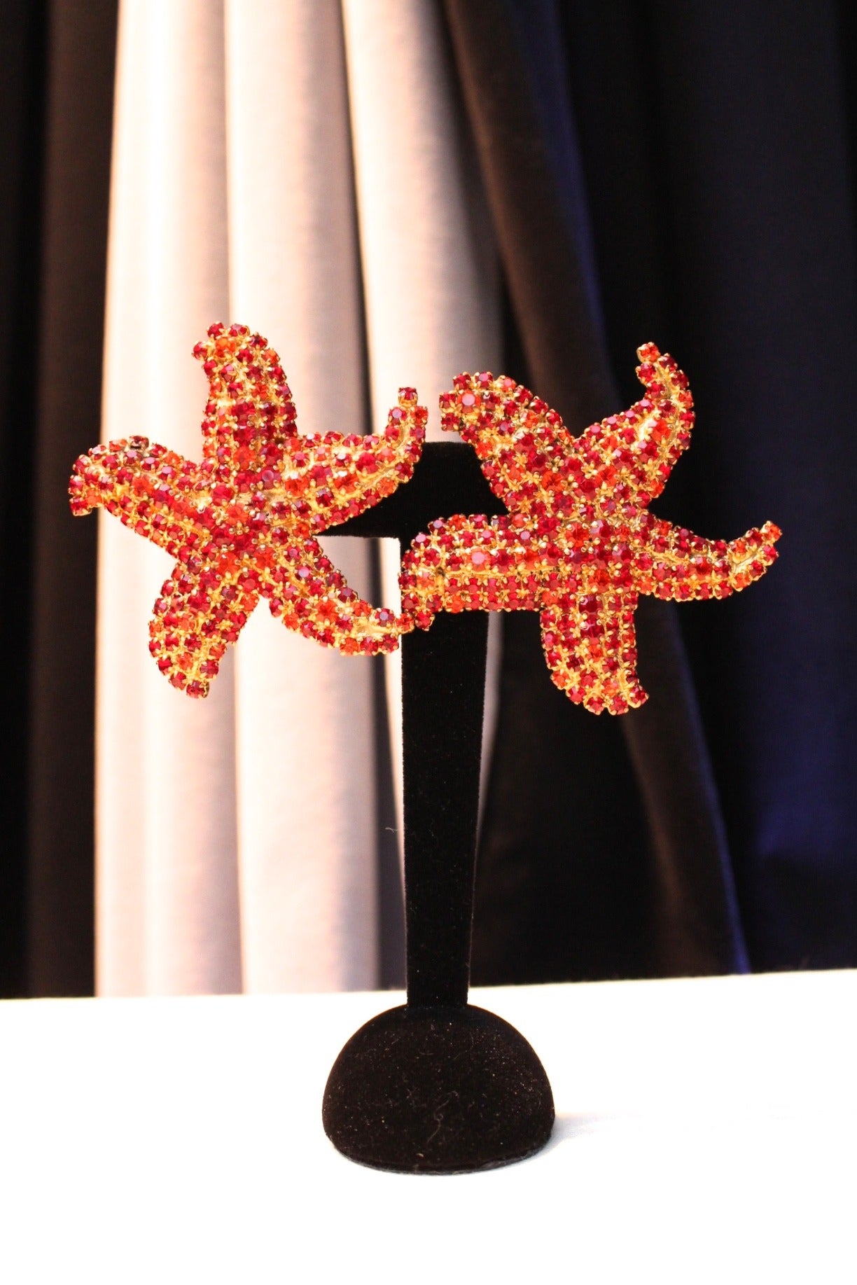 Pair of clip-on earrings Yves Saint Laurent signed YSL, in a shape of starfishes, composed of gold metal paved with dark red and orange crystals. 

These earrings are probably from the collection 1989. 
A piece of tape with the number '946' is