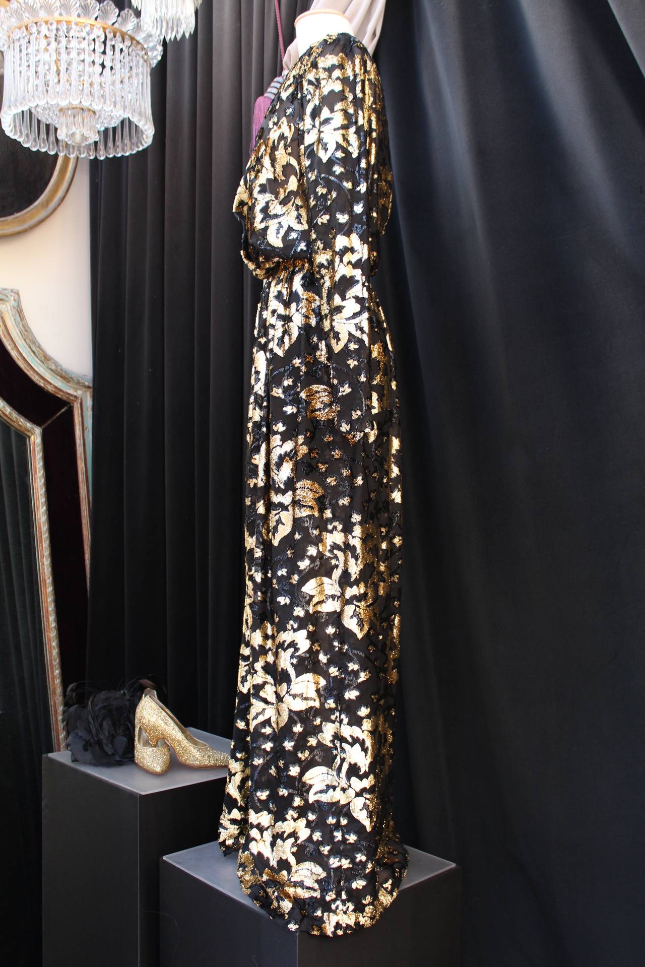 GIVENCHY NOUVELLE BOUTIQUE (Made in France) Long evening gown composed of black and lamé (gold) silk muslin and velvet figuring a floral print. 
Long sleeves ended with a black zippers. Wide V neckline with a small and discrete black push button