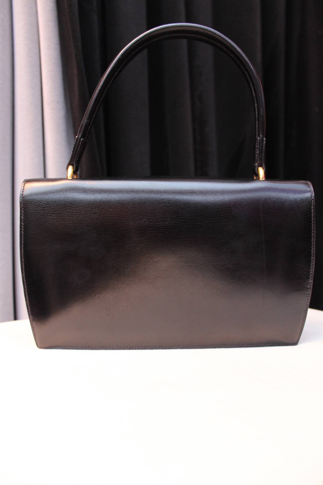 HERMES ( Paris) Rectangular black leather handbag from the 1960's centered with a gold plated metal clasp and held by a single handle.

The inner lining is composed of black lambskin leather. It includes two flaps and four inside pockets,