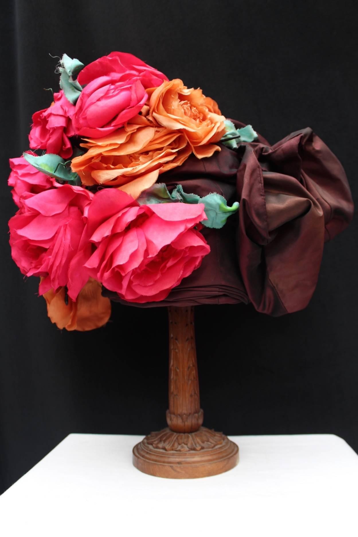 JEAN PATOU Haute Couture ( Made in France) – Magnificient hat Haute couture from the runway  in drapped silk taffetas comprised of burgundy voluminous bows and pink, orange and green flowers and leaves. 

The hat  comes with the name tag of the