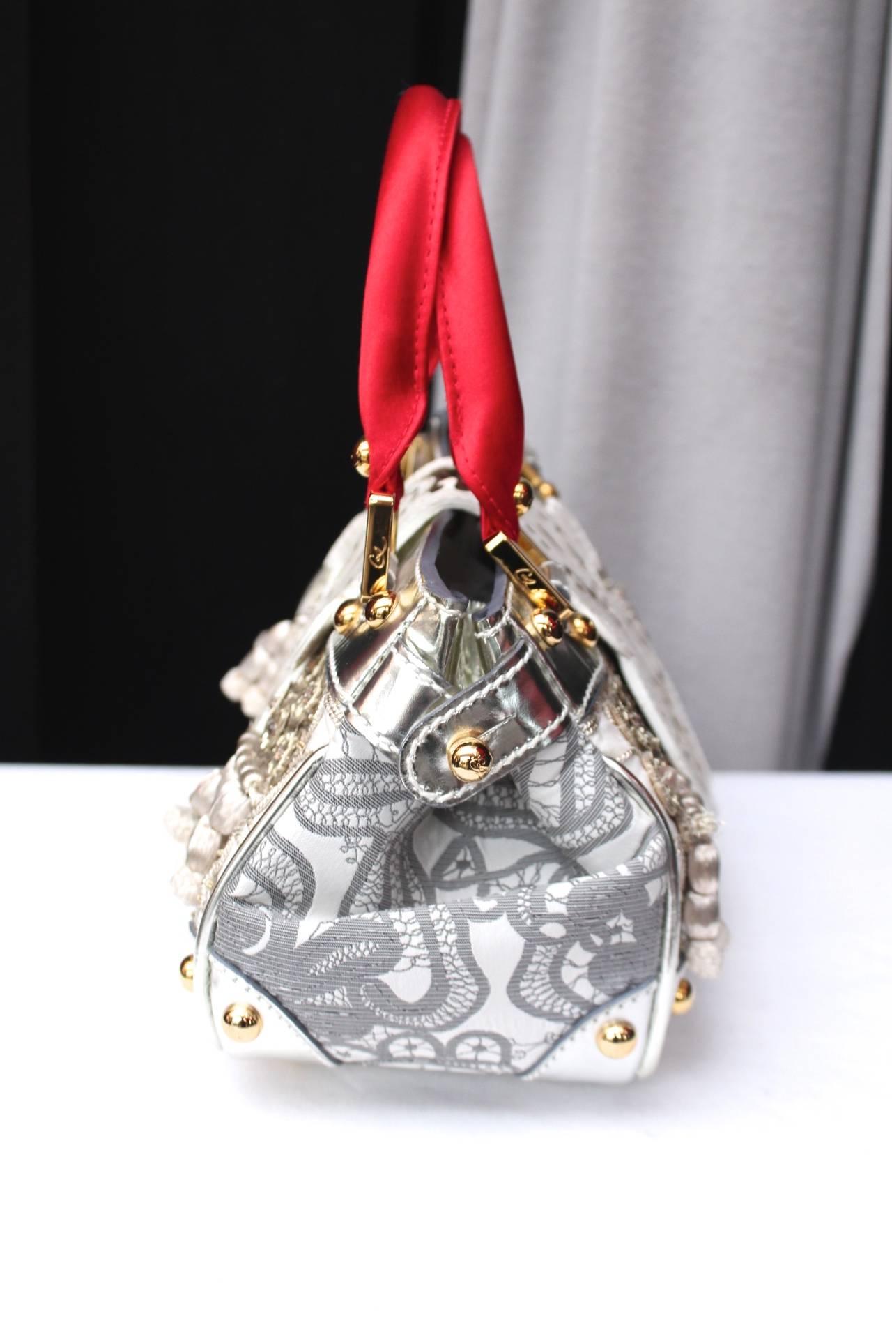 CHRISTIAN LACROIX (Made in Italy) Very rare and exceptional handbag comprising of two red silk top handles, silver patent leather embroidered with sequins and pearls in a floral motif and grey tassels. It fastens with a closing flap in white patent