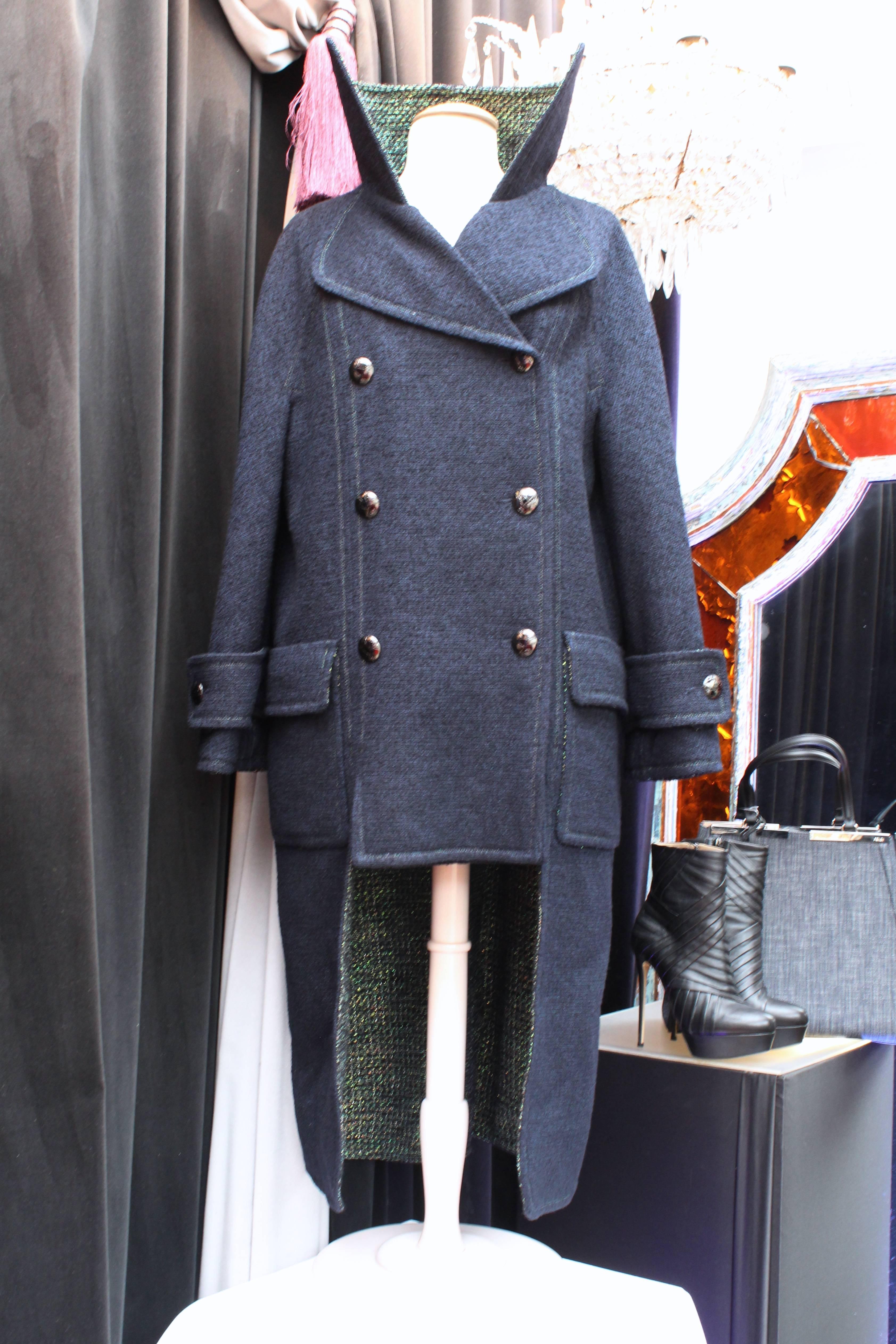 CHANEL (Made in France) Oversized coat in navy blue wool tweed in the outside and iridescent green lining, in a military style. 

It has a double collar, two large pockets in the front and is longer in the back with quite edgy cuts. 

This coat