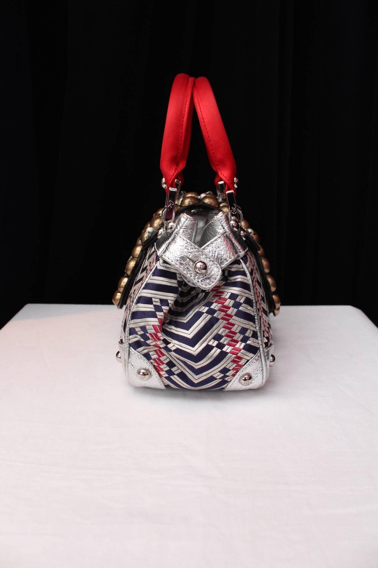 CHRISTIAN LACROIX Very rare and exceptional handbag comprising of two red silk top handles, silver leather, a geometric weaving fabric in navy blue, white and red color adorned with a arabesque shape flap in black leather embroidered with metal