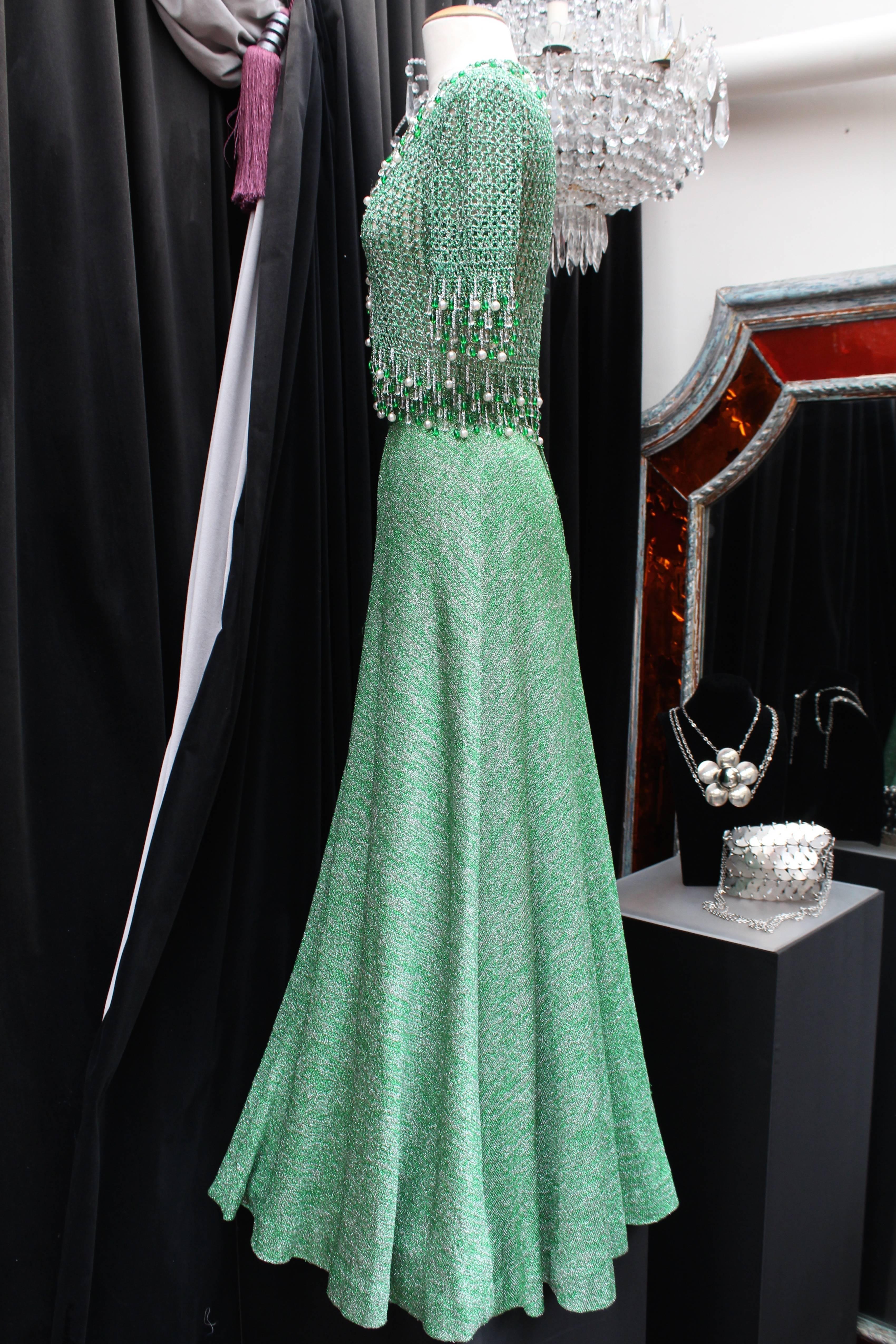LORIS AZZARO (Made in France) Set consisting of a long skirt and a jacket in green and silver lurex crochet, dating from the 1970s.

The vest with short sleeves and V-neck, is constructed with a large mesh crochet in lurex and adorned on the