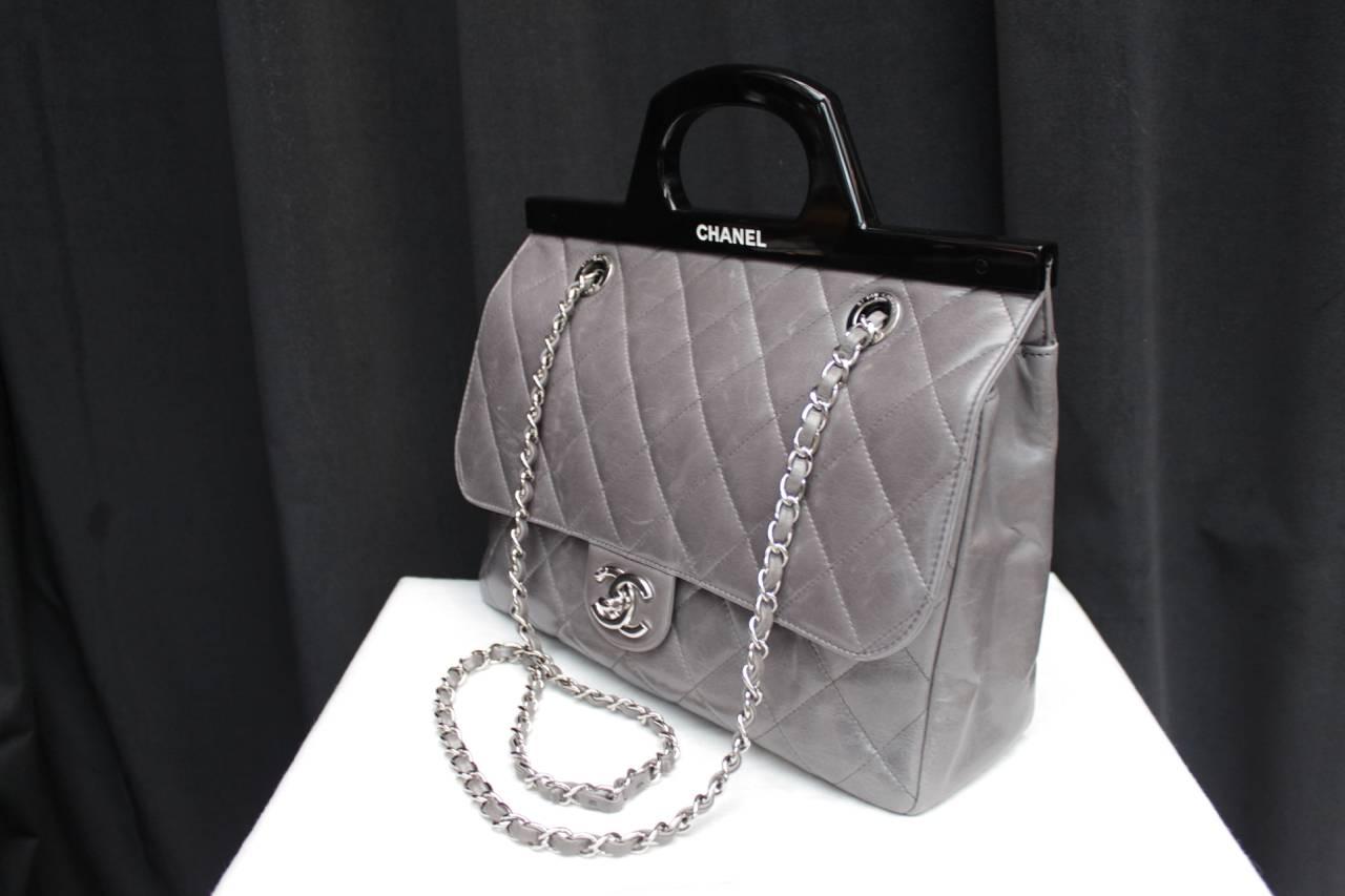 CHANEL (Made in Italy) Large shoulder bag  model Timeless in grey quilted  lambskin adoned with a black resin handle on the top of the bag engraved in white with Chanel. 
It also features a double silver metallic sliding handle interlaced with gray