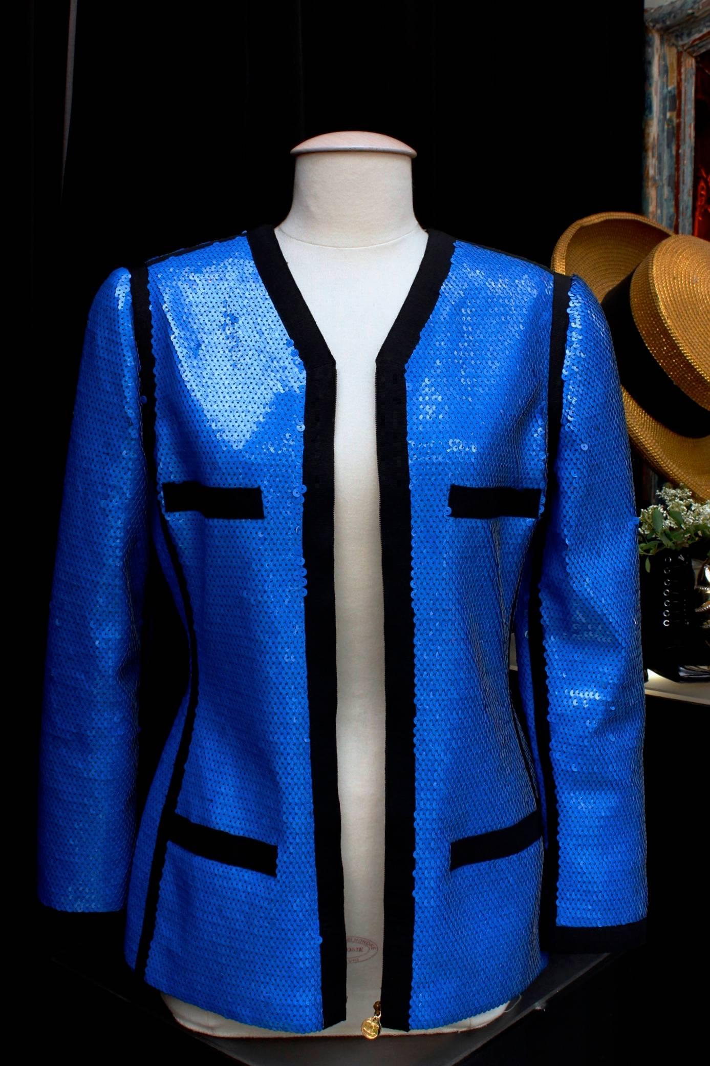 CHANEL BOUTIQUE Rare blue sequins all-over jacket with black galloons, V-neckline, long sleeves, concealed gilt zip fastening, two false pockets. 

Black silk lining

Collection Spring-Summer 1991. 
Similar model worn by Linda Evengelista and