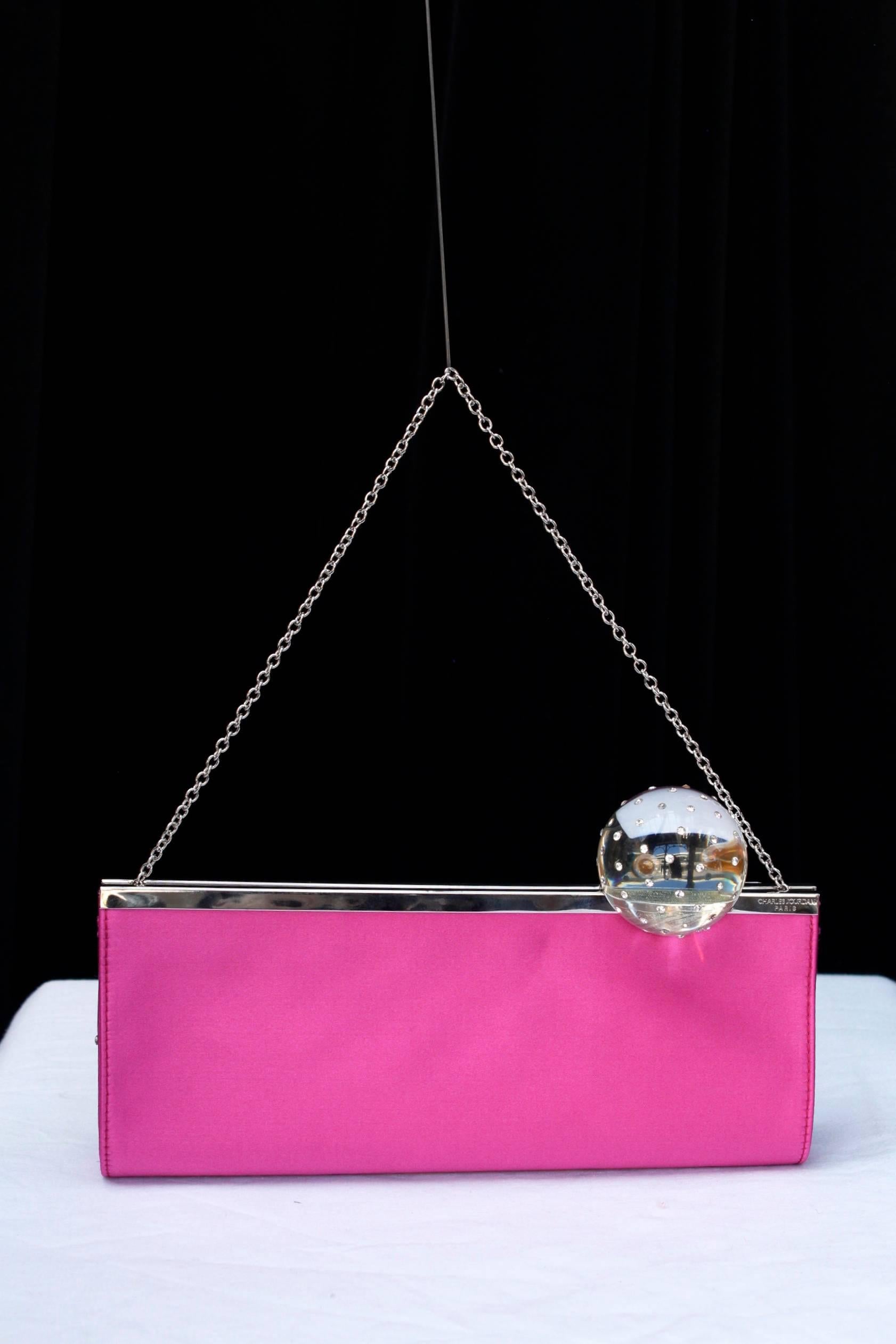 CHARLES JOURDAN PARIS – Evening leather clutch covered with fuchsia satin and decorated with a long silver plated clasp topped with a large transparent resin sphere with rhinestones inlay. The brand name is chiseled on the clasp.

Dark grey satin