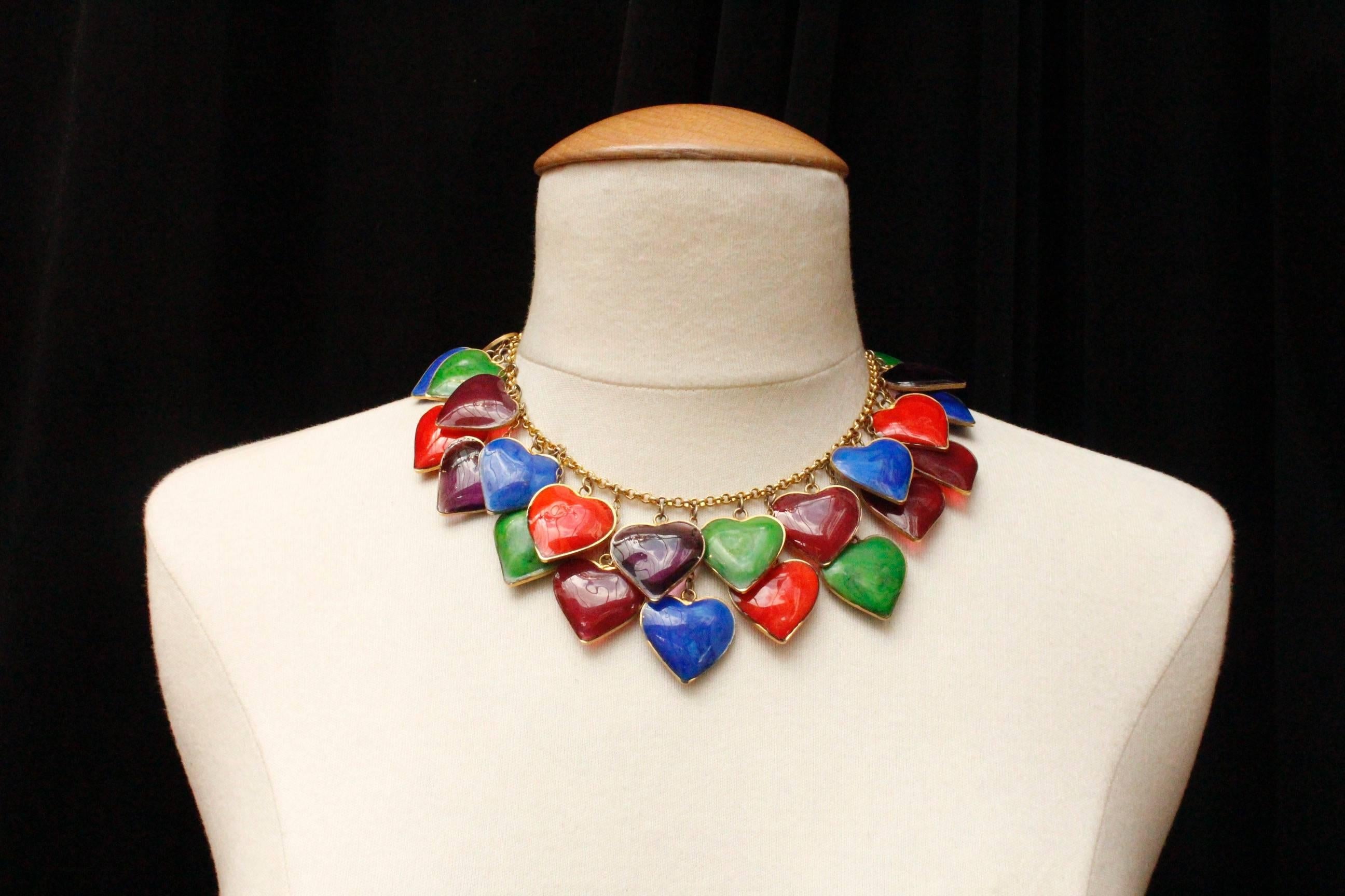 YVES SAINT LAURENT (Made in France) – Choker composed of a gilded metal chain embellished with thirty opaque or transparent glass paste hearts in green, blue, red and plum colors, set in gilded metal. The hearts are positioned in staggered rows.