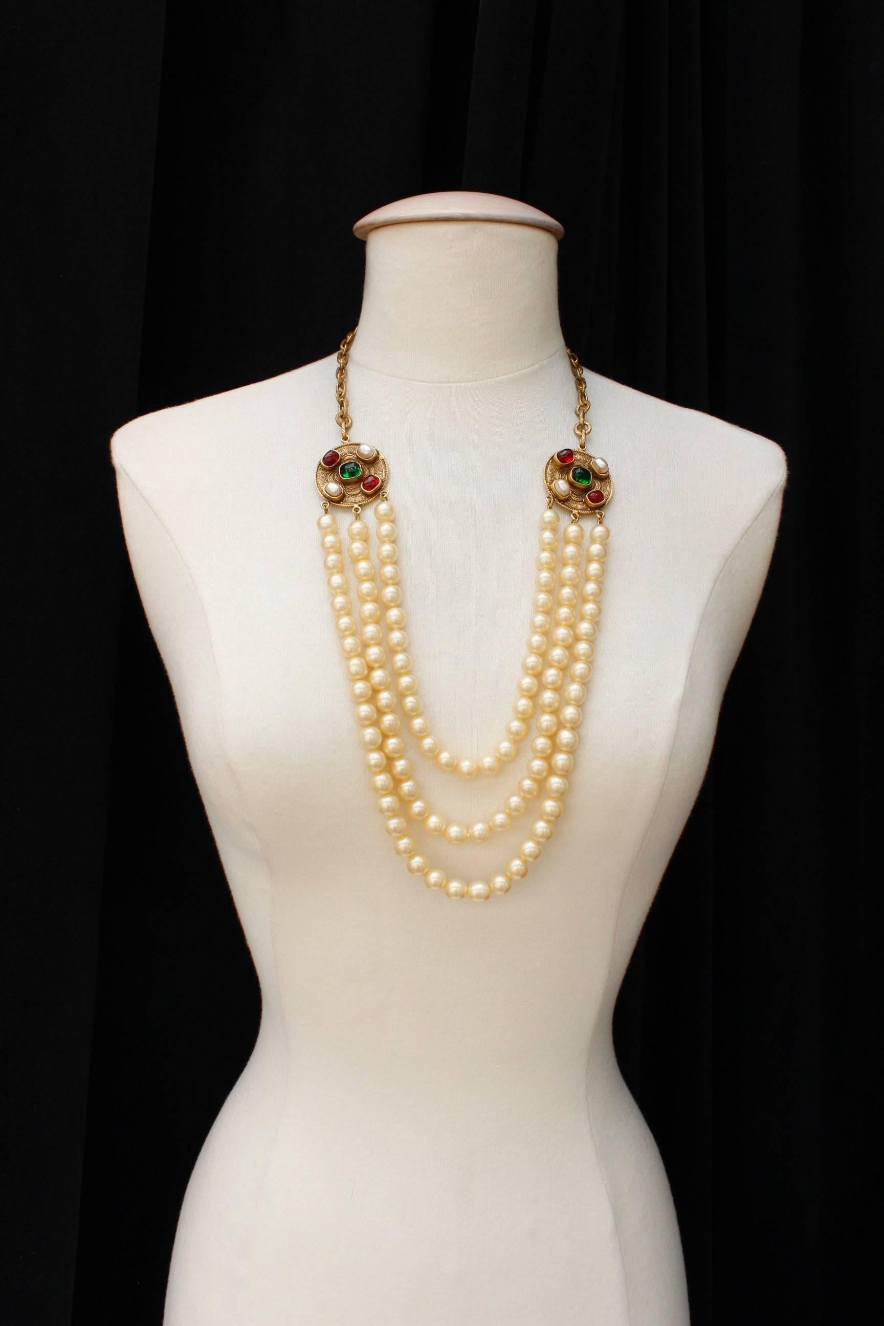 CHANEL (Made in France) Gorgeous long necklace composed of three strands of knot mounted pearly beads. Different strands are linked with two gilded metal medallions. Medallions are made of faux pearl cabochons, and red and green glass paste