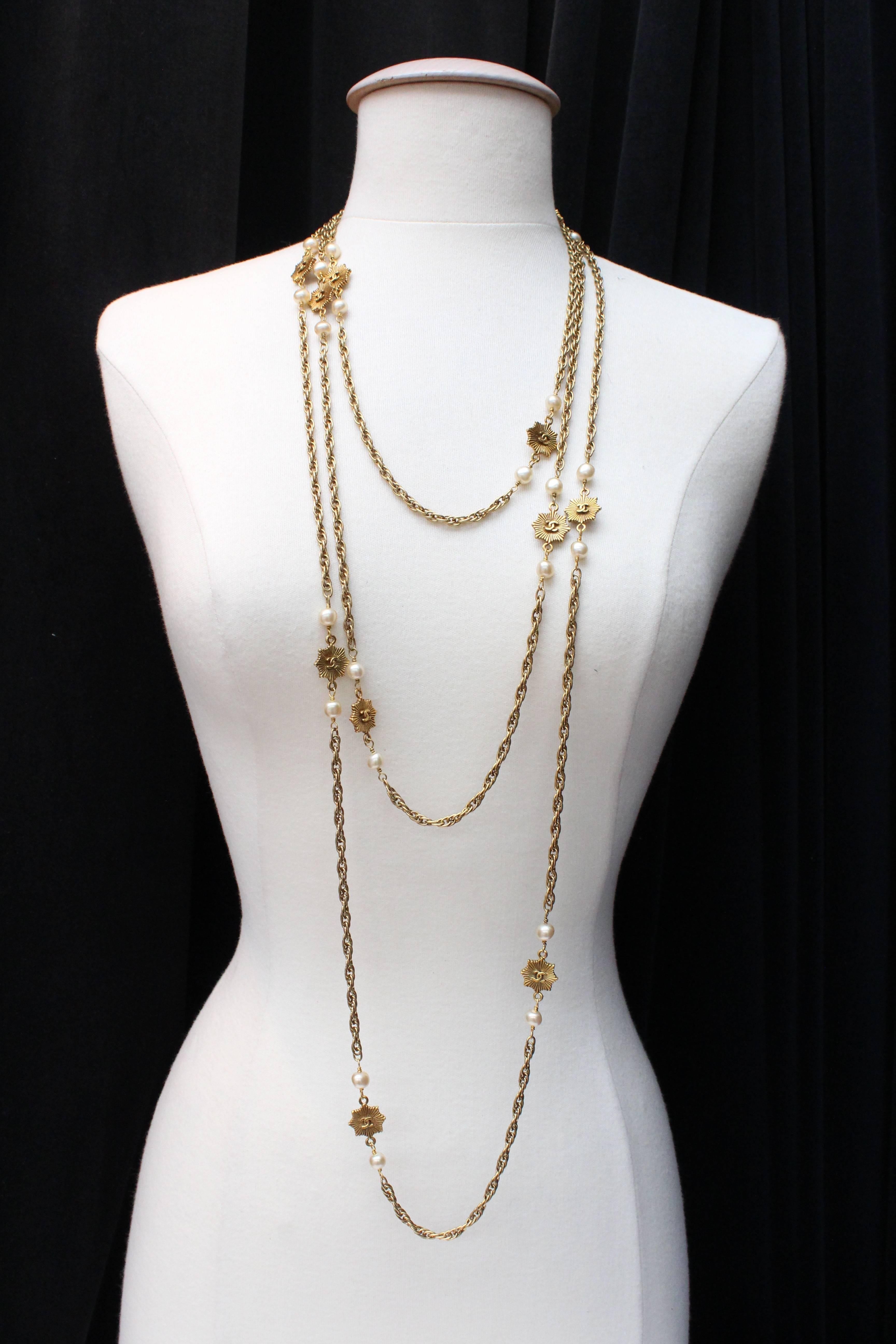 CHANEL (Made in France) Long sautoir necklace composed of a twisted gilded metal chain in antique gold color, alternating with small pearly beads and striated gilded metal stars.  A CC logo is encrusted in the center of the stars. The sautoir  is
