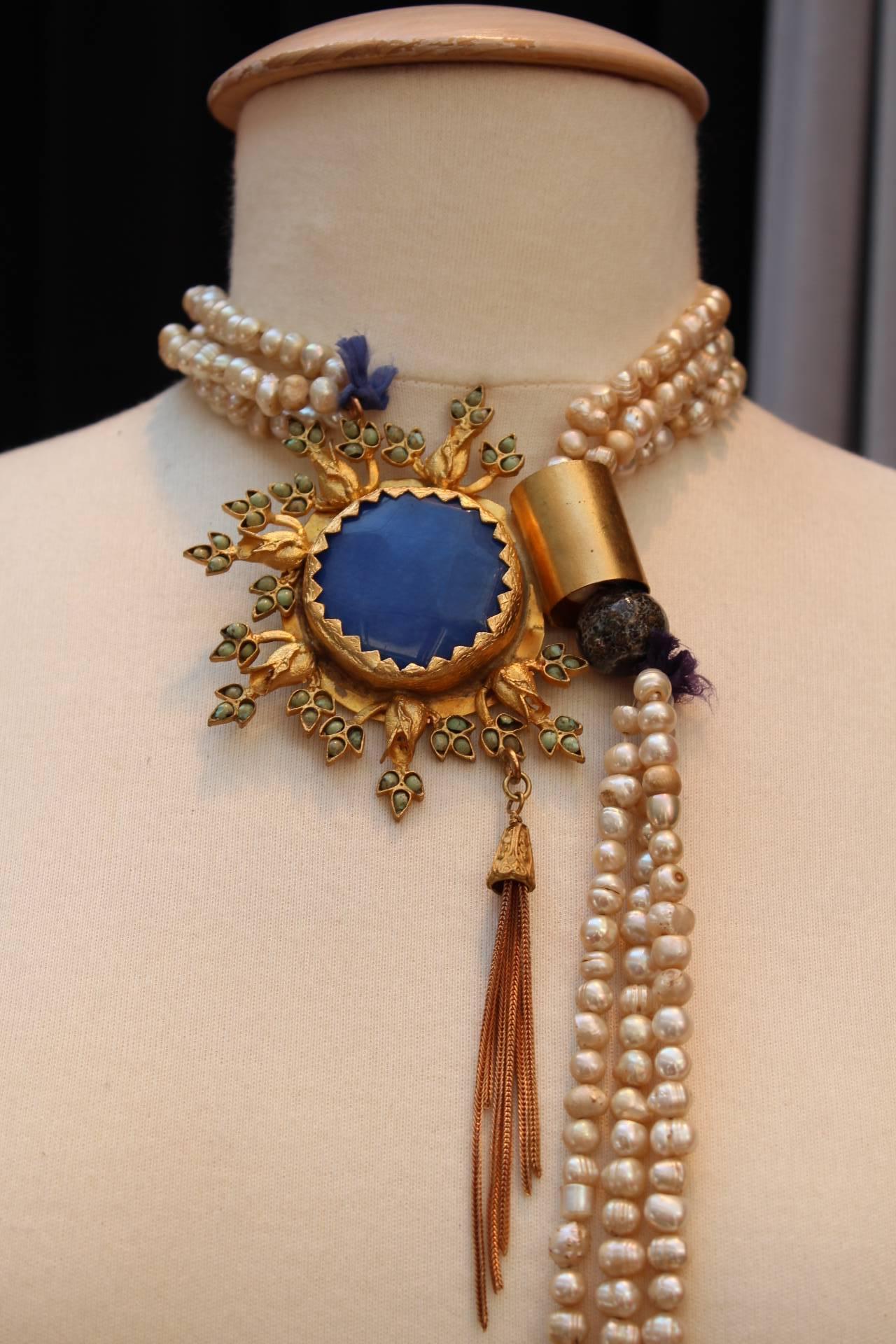 OSCAR DE LA RENTA RUNWAY Tie necklace consisting of pearly and pinkish baroque beads, with a removable medallion in the shape of a gilded metal sun, decorated with blue and green glass paste holding a goldtone chain tassel. 

Circa 1980.