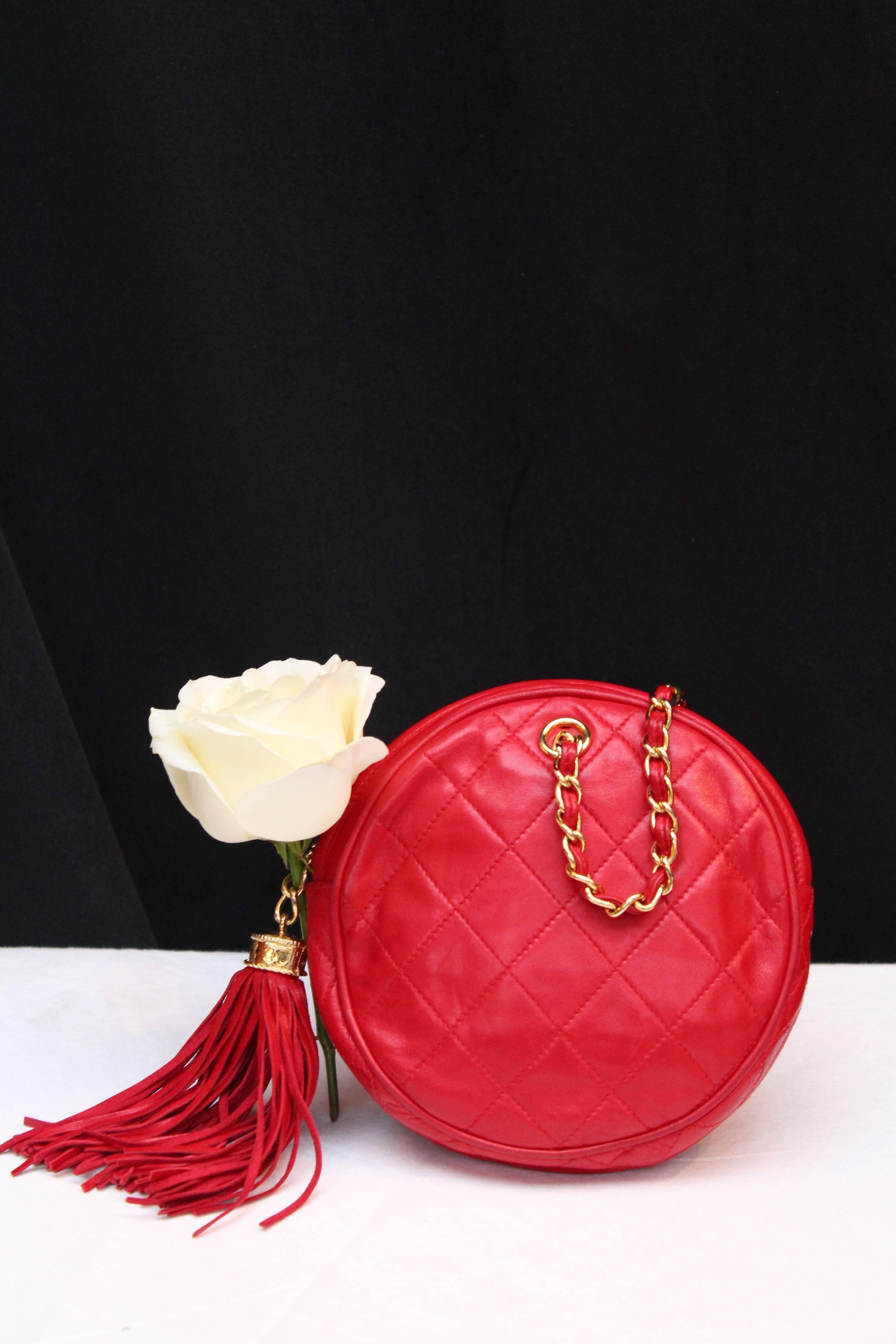 CHANEL (Made in Italy) Nice small round evening hand bag made of red quilted leather, with a short gilded metal chain entwined with red leather. It opens with a gilded metal zip decorated with a red leather tassel. Red leather lining, bearing the