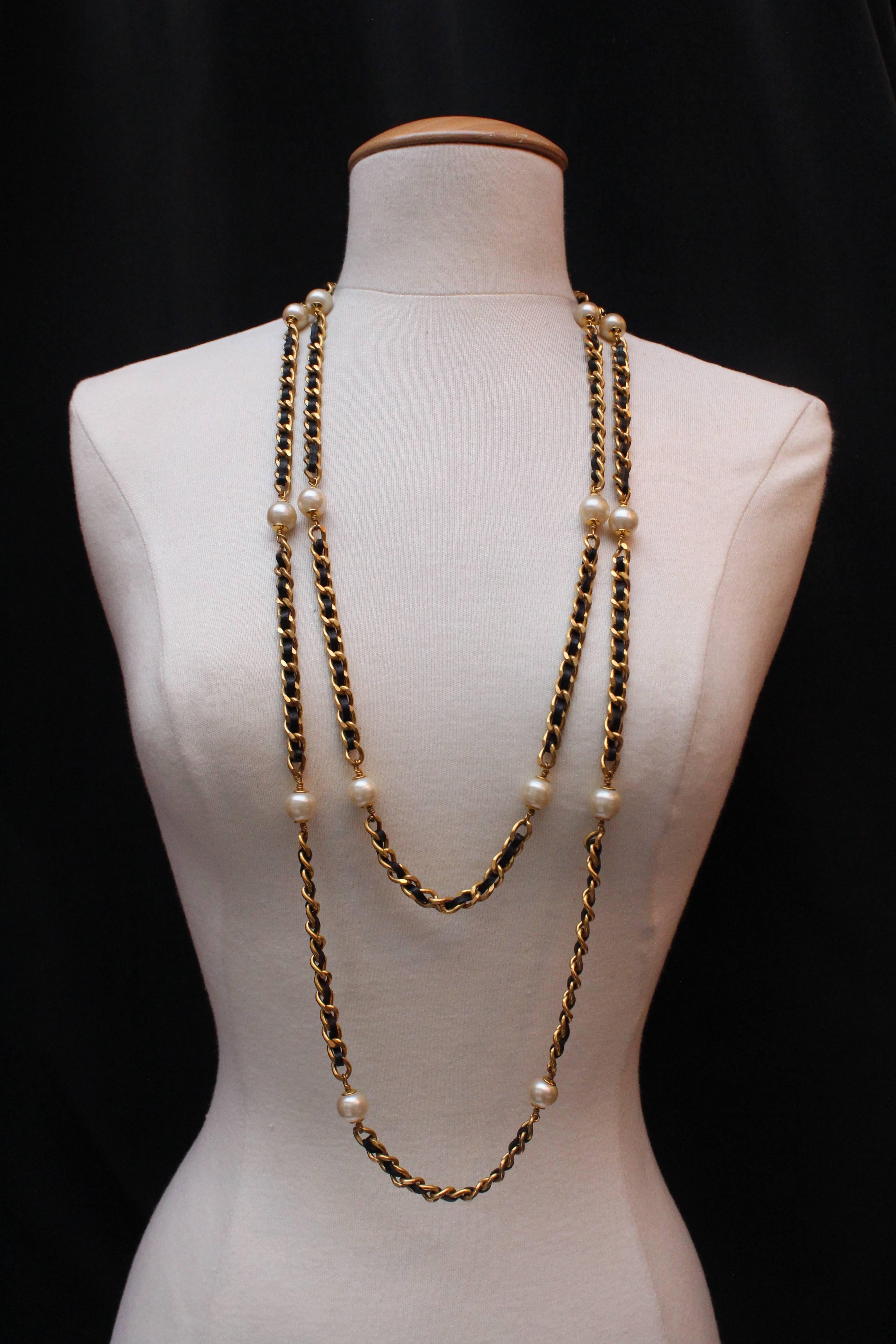 CHANEL (Made in France) Long sautoir necklace composed of a gilded metal chain entwined with black leather. This type of  work combining gilded metal and black leather characterized the iconic fashion house in the 1990’s. The necklace is embellished