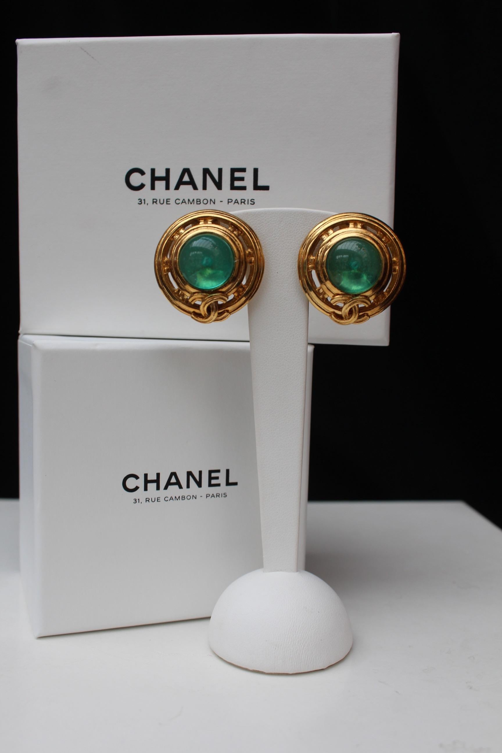 CHANEL (Made in France) Very nice vintage clip-on earrings made of openwork gilded metal, embellished with a central cabochon in light green glass paste, and a small CC logo at the bottom. Signed at the back.

1996 Spring-Summer