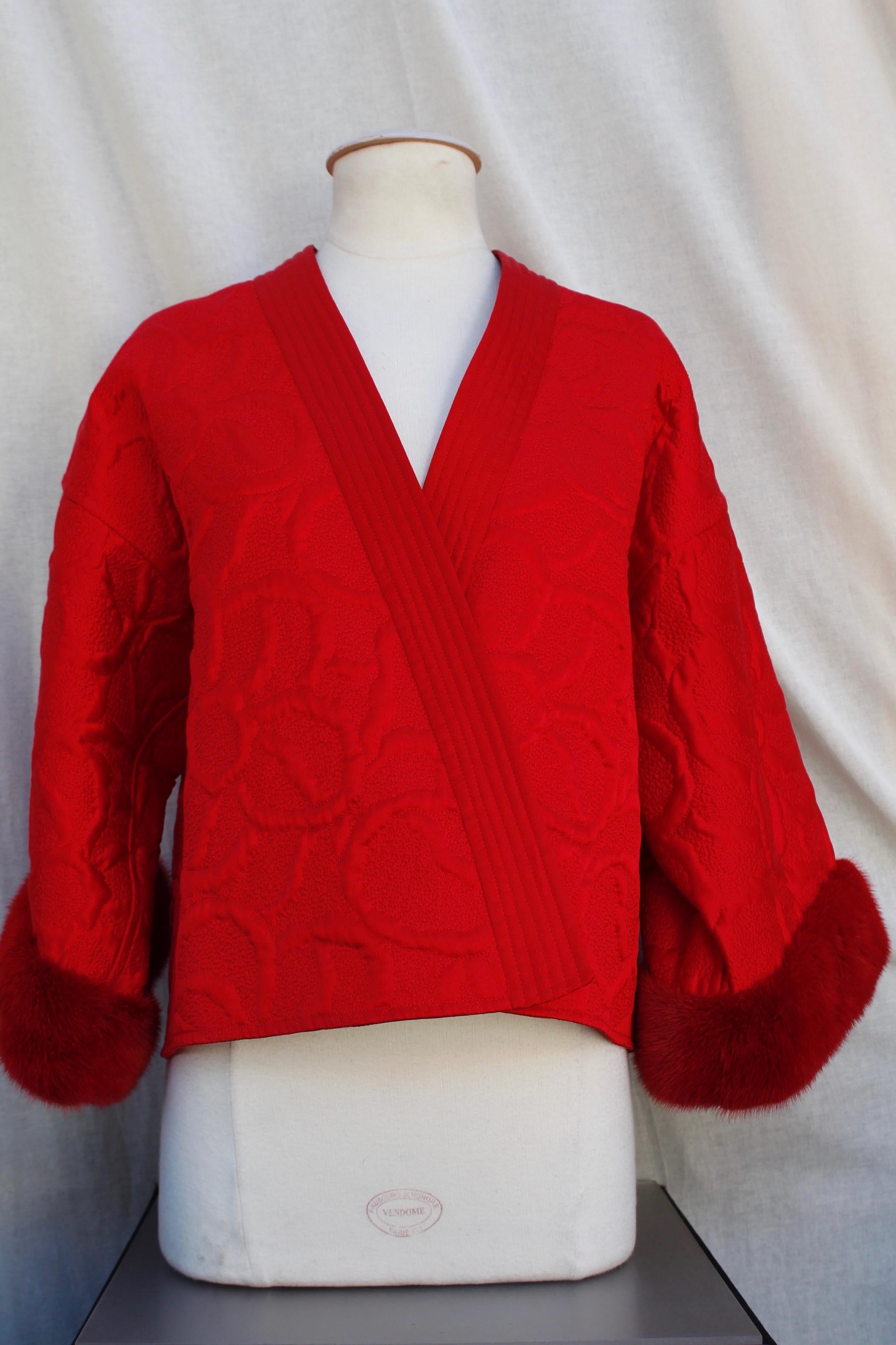 VALENTINO BOUTIQUE – Beautiful kimono-shaped short jacket with three-fourth pagoda sleeves and openings under the arms. It is composed of embossed over stitched red satin representing relief flowers. The cuffs are embellished with red mink.

Circa