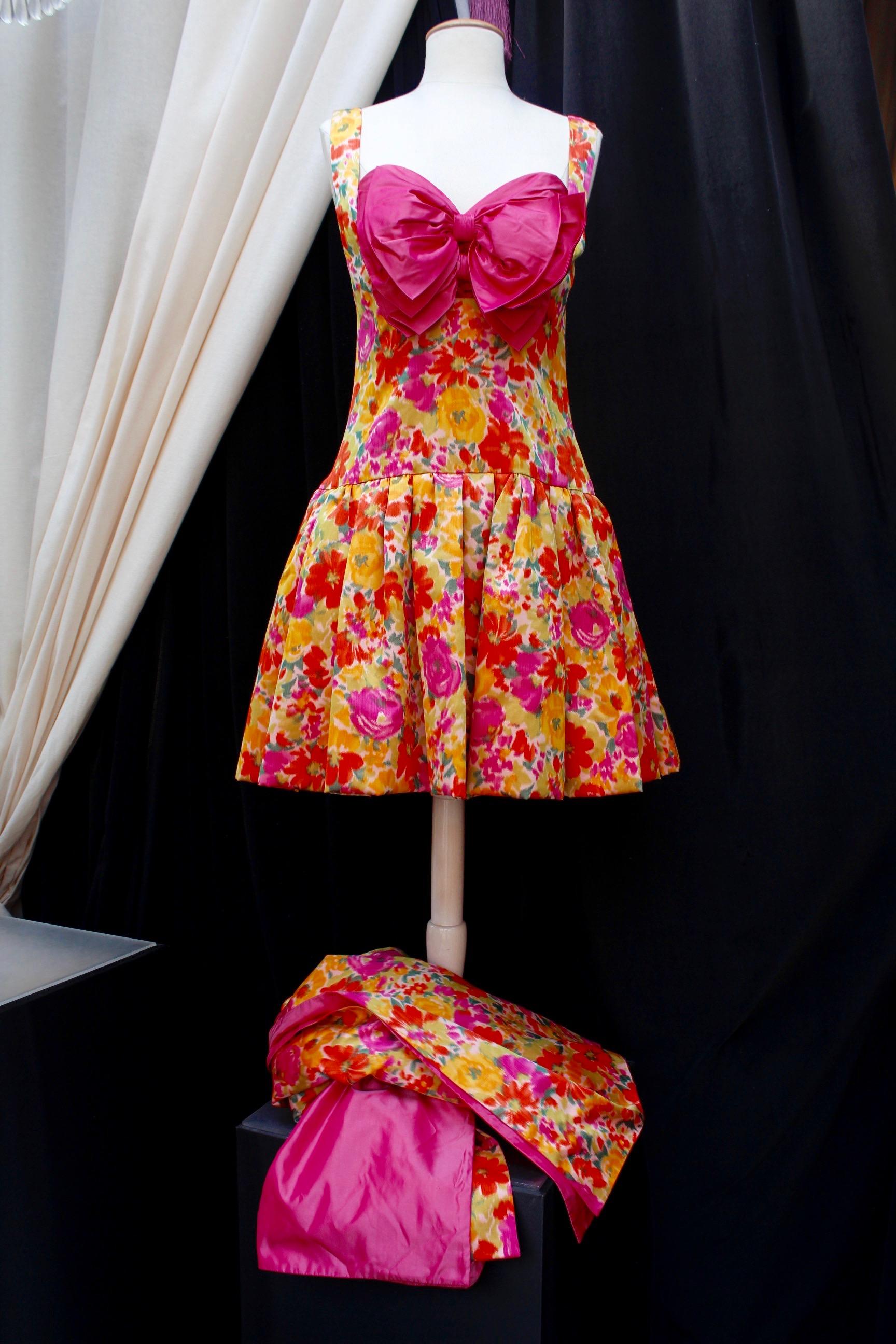 NINA RICCI (Made in France) Lovely short skater dress with thin shoulder straps and a lovely heart-shaped neckline. It is composed of a silk taffeta with floral pattern print in orange, pink, yellow and green colors. It is decorated with a pleated