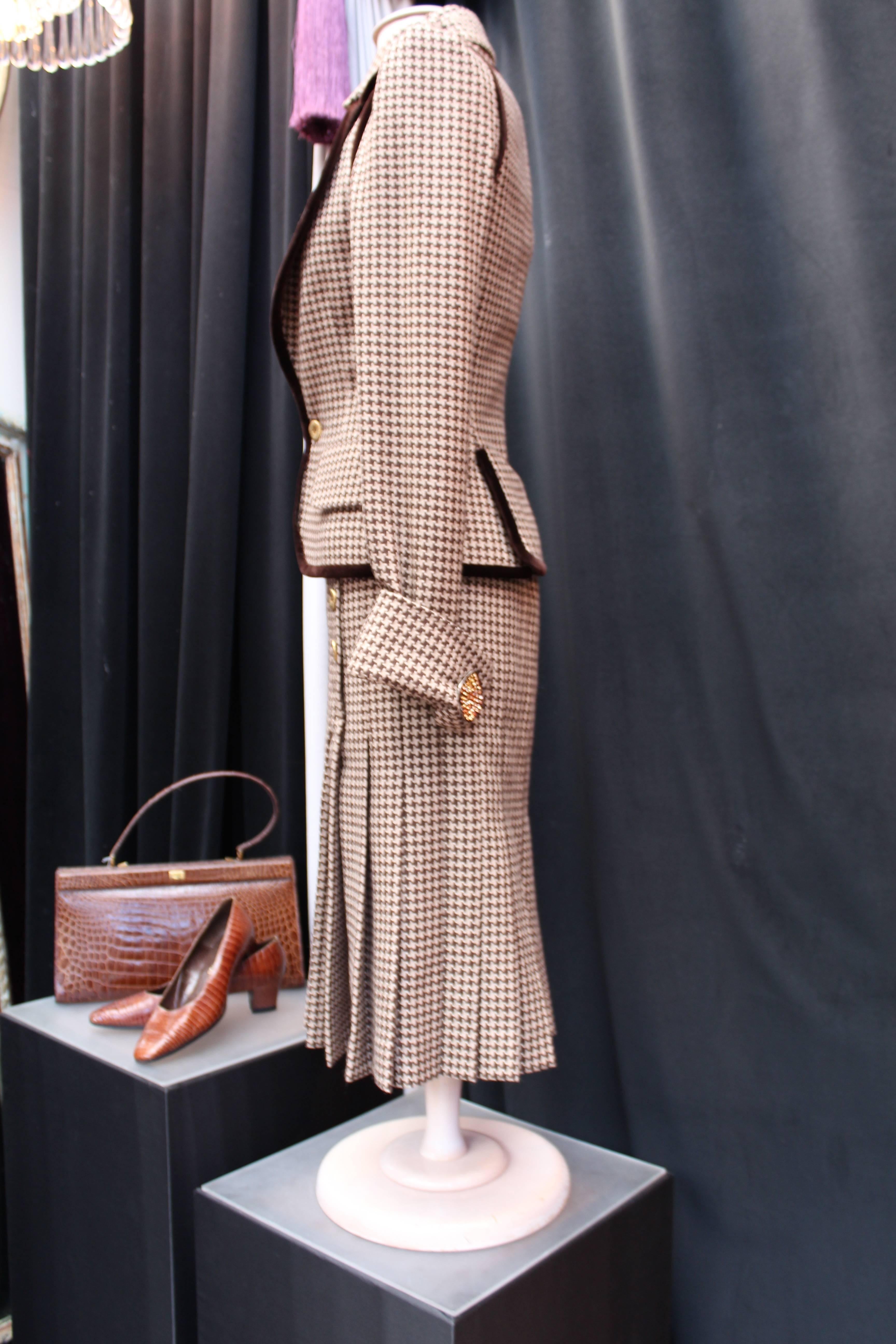 JEAN-LOUIS SCHERRER (Fall 2004-2005 Ready-to-wear) Long pleated dress and matching sleeveless jacket ensemble comprised of brown and ecru Houndstooth wool adorned with chocolate velvet galloon and large buttons.

The buttons on the sleeves are