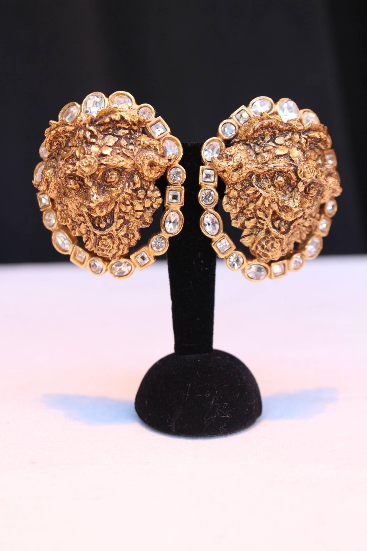CHRISTIAN DIOR BOUTIQUE Magnificent pair of clip-on earrings comprised of hammered gilt metal figuring a head of a faun circled by a round of white crystals. 
This is a work by Robert Goossens in the 1980s. 

Very good condition.