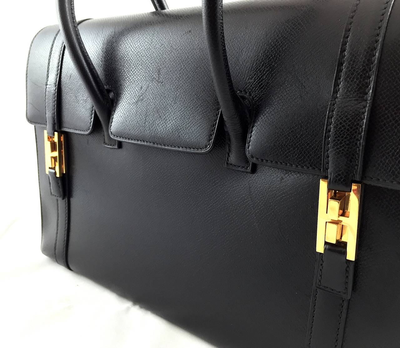 Gorgeous Hermès 32 Drag Bag in black epsom leather from 2003 (stamp square G). This hard-to-find and very convenient handbag by Hermès features gold-tone hardware, double leather straps, and a flap closure with two H clasps at front. The interior