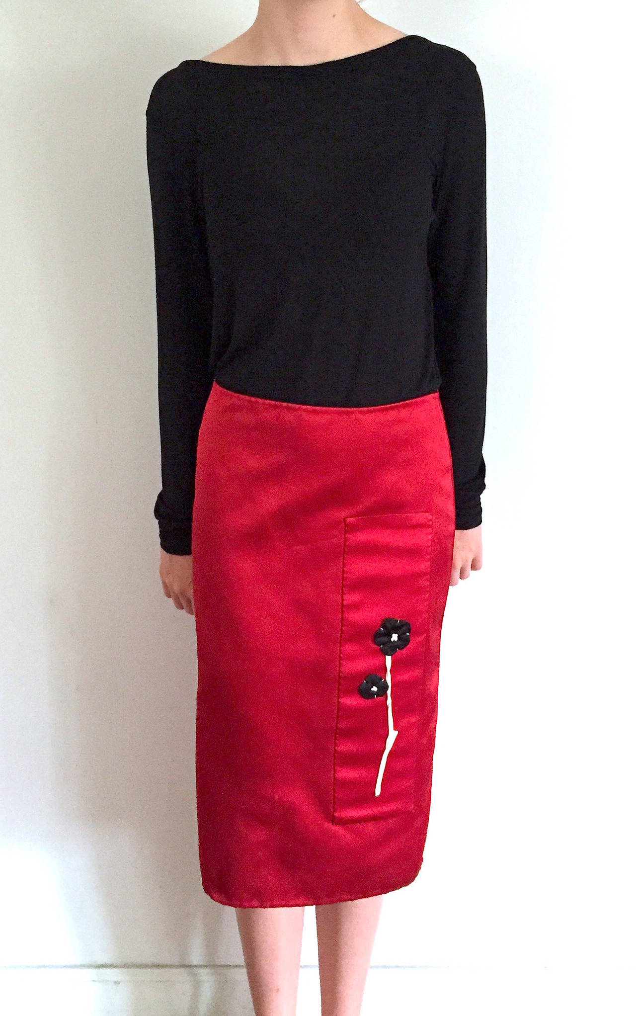 Prada runway red satin skirt with black and white flower applique from the mid-2000s. Features a back zippered closure and slit at bottom back, and hits below the knee.