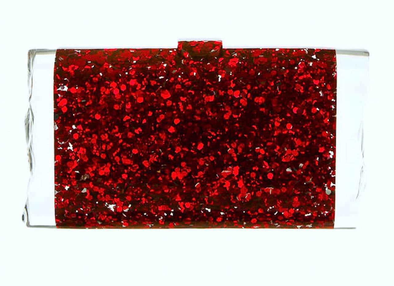Edie Parker, a red carpet favorite, is a brand of vintage-inspired clutches and handbags based in New York City founded in 2010 by Brett Heyman. 

The clutch is constructed in hand poured acrylic with red glitter. It features an acrylic tab