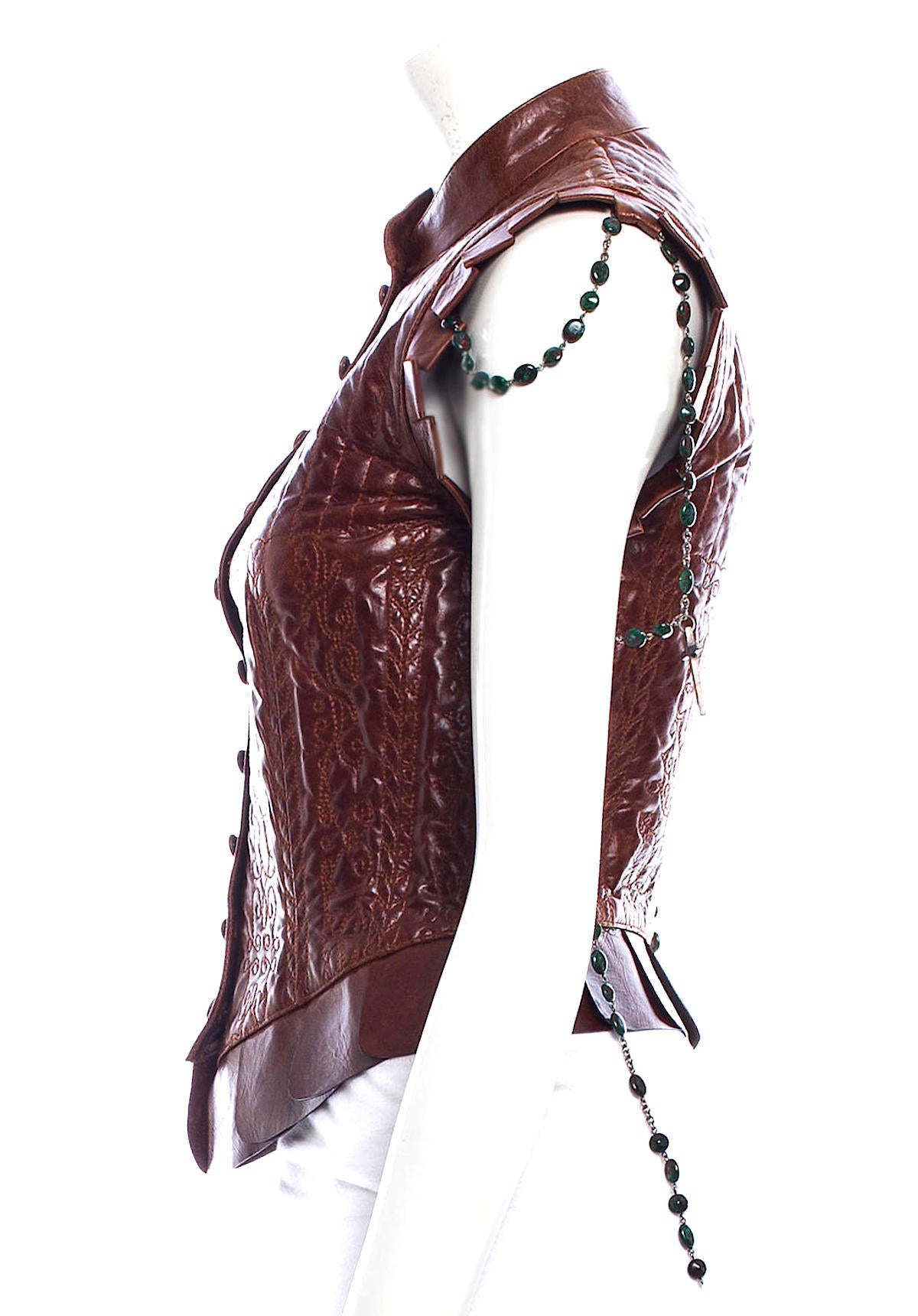 Fierce Alexander McQueen dark brown leather vest from the Spring 2003 Irere Collection and outfit 6 from the runway show. The vest features intricate quilting, front button closure, green gunmetal chain at sleeves, pleated cut out trim, and a