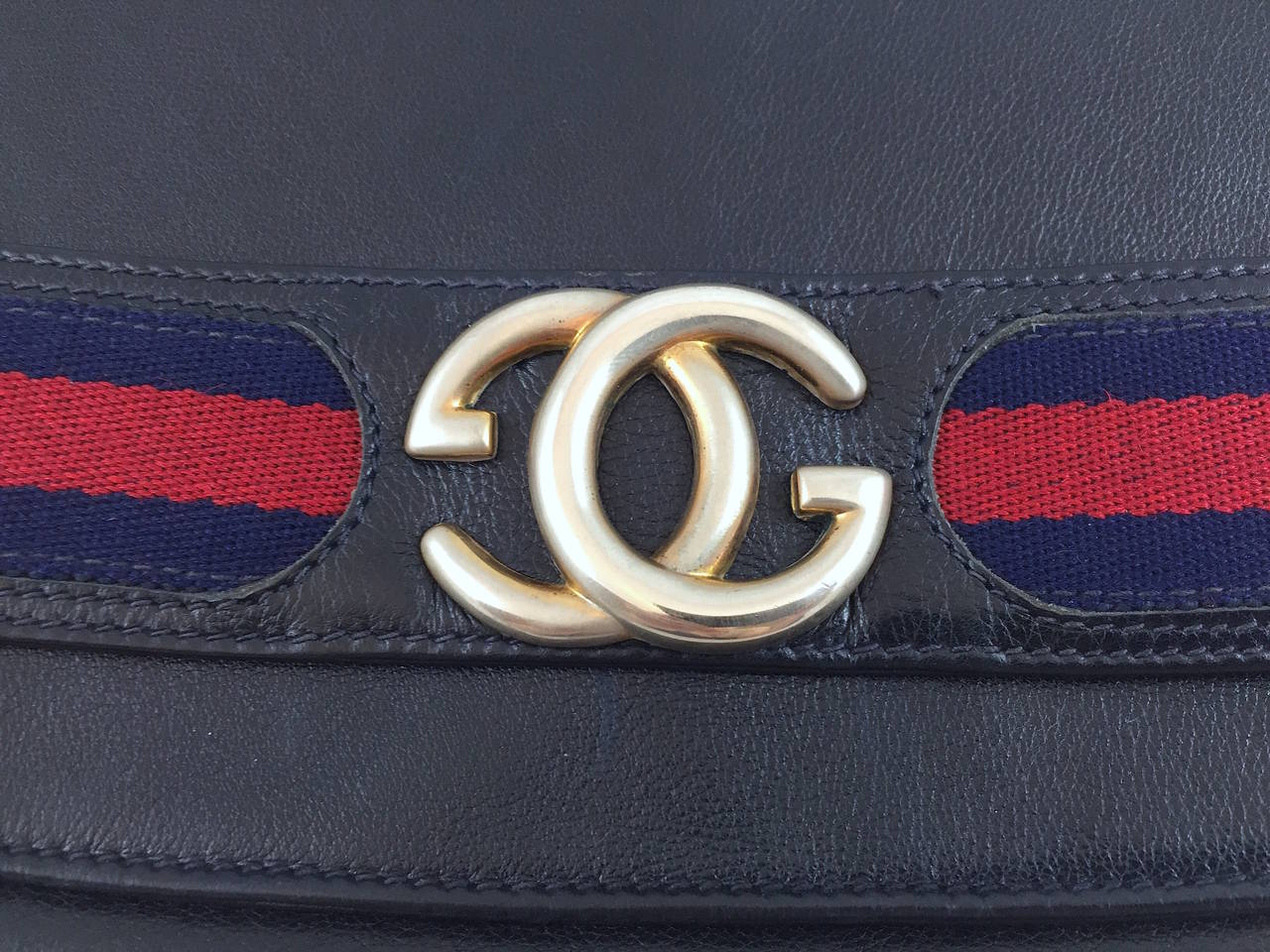 Navy blue leather Gucci vintage clutch with signature navy and red web trim, gold-tone hardware, navy suede lining, interior zip pocket, and GG accent at front flap closure. Circa 1960s.

Measurements: Height 7