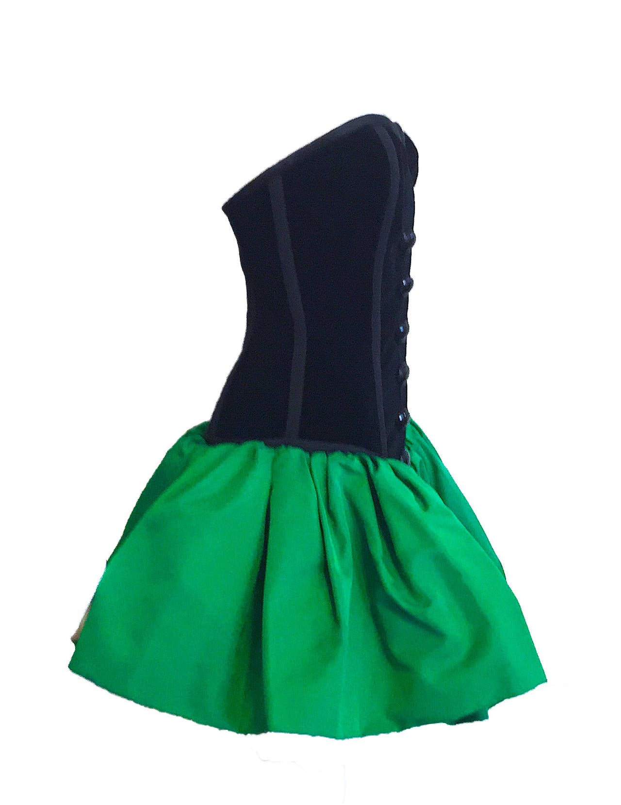Rare, museum quality Yves Saint Laurent Rive Gauche YSL cocktail dress, circa 1986. This stunning dress features a velvet bustier with trim, black button embellishments and front zippered closure. The skirt is a vibrant emerald green taffeta with a