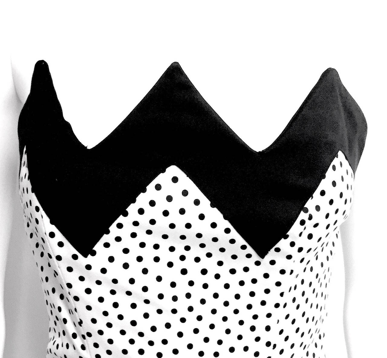 Vintage Lanvin 1980s strapless cocktail dress. Timeless and whimsical, the dress features a black zig zag neckline, fitted bodice, boning, and is white with small black polka dots. It includes a black fishnet underlay and an a-line skirt. It has a