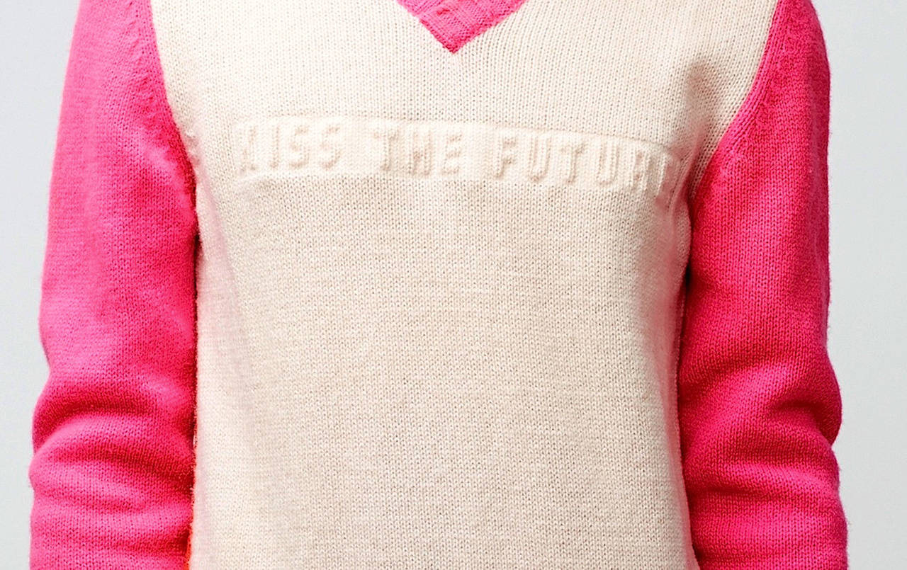 Walter Van Beirendonck sweater from the 1998 Autumn/Winter collection. It features a ribbed v-neck, cream colored front, neon pink odd length sleeves, red back and a foam insert ‘kiss the future’ logo inlaid on the chest.

Measurements: 
About